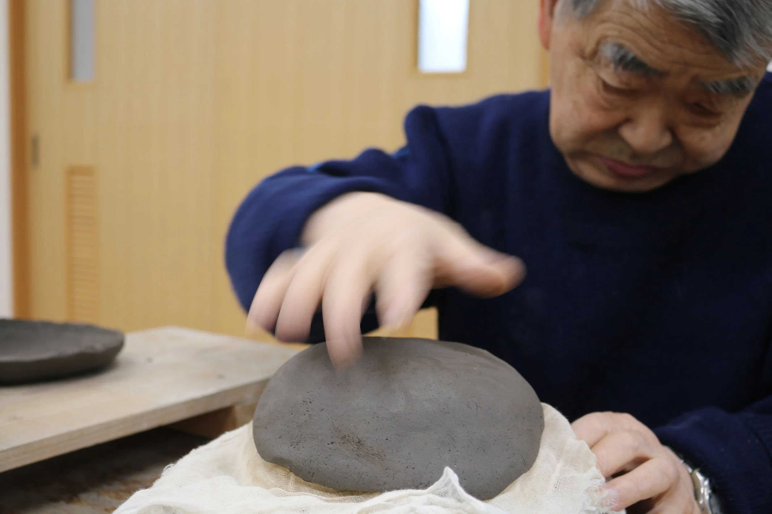 a potter at shigaraki seinenryo shaping a mound of shigaraki clay by hand