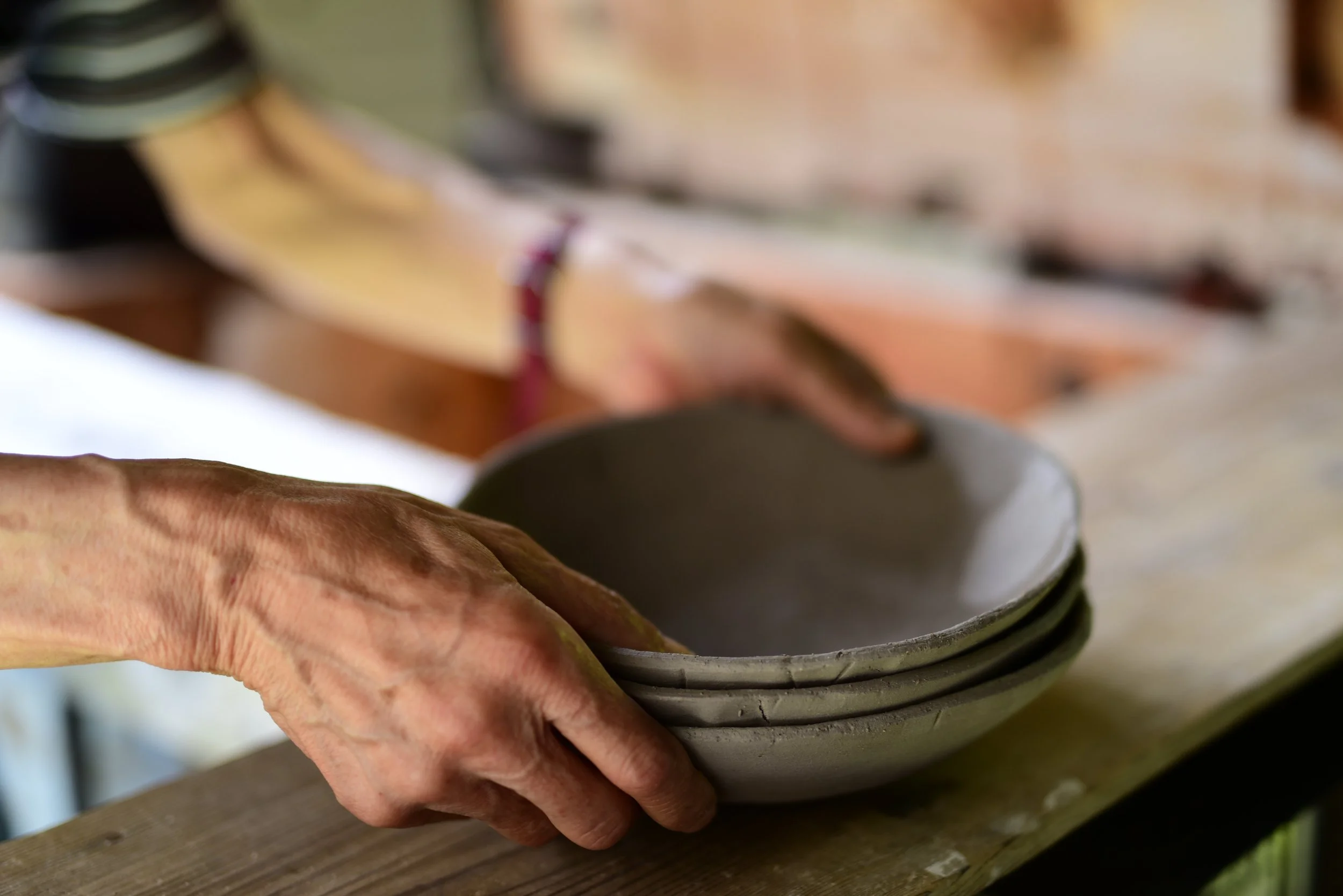 Close-up of a person's hand shaping a ceramic bowl on a pottery wheel.