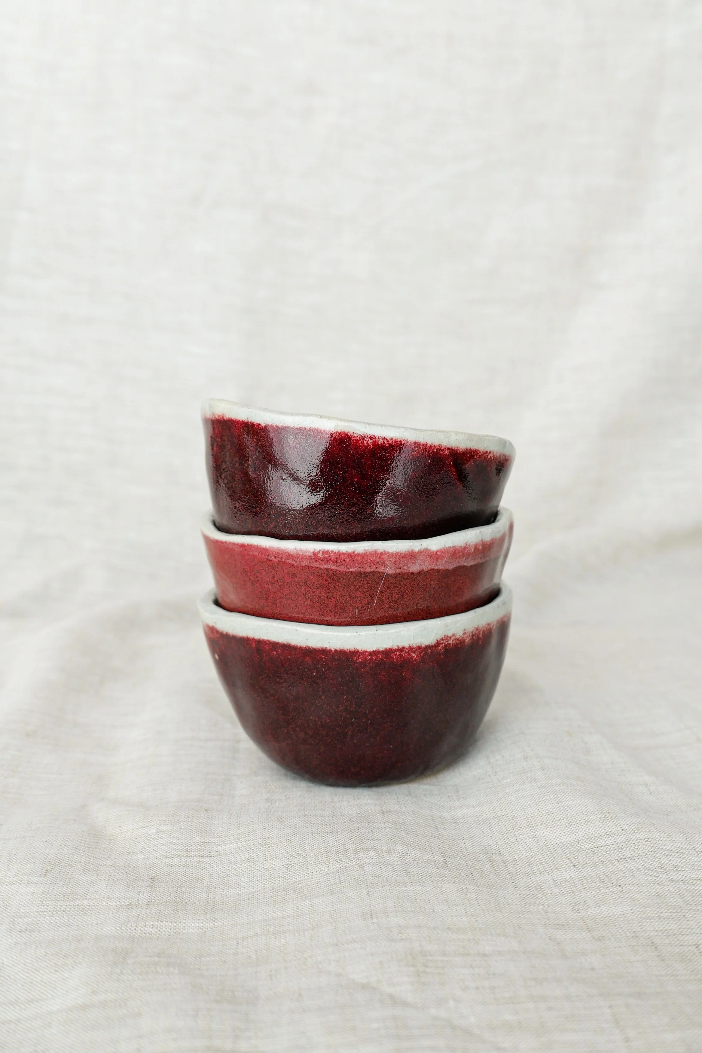 Stacked ceramic bowls with red and black glaze on a white background.