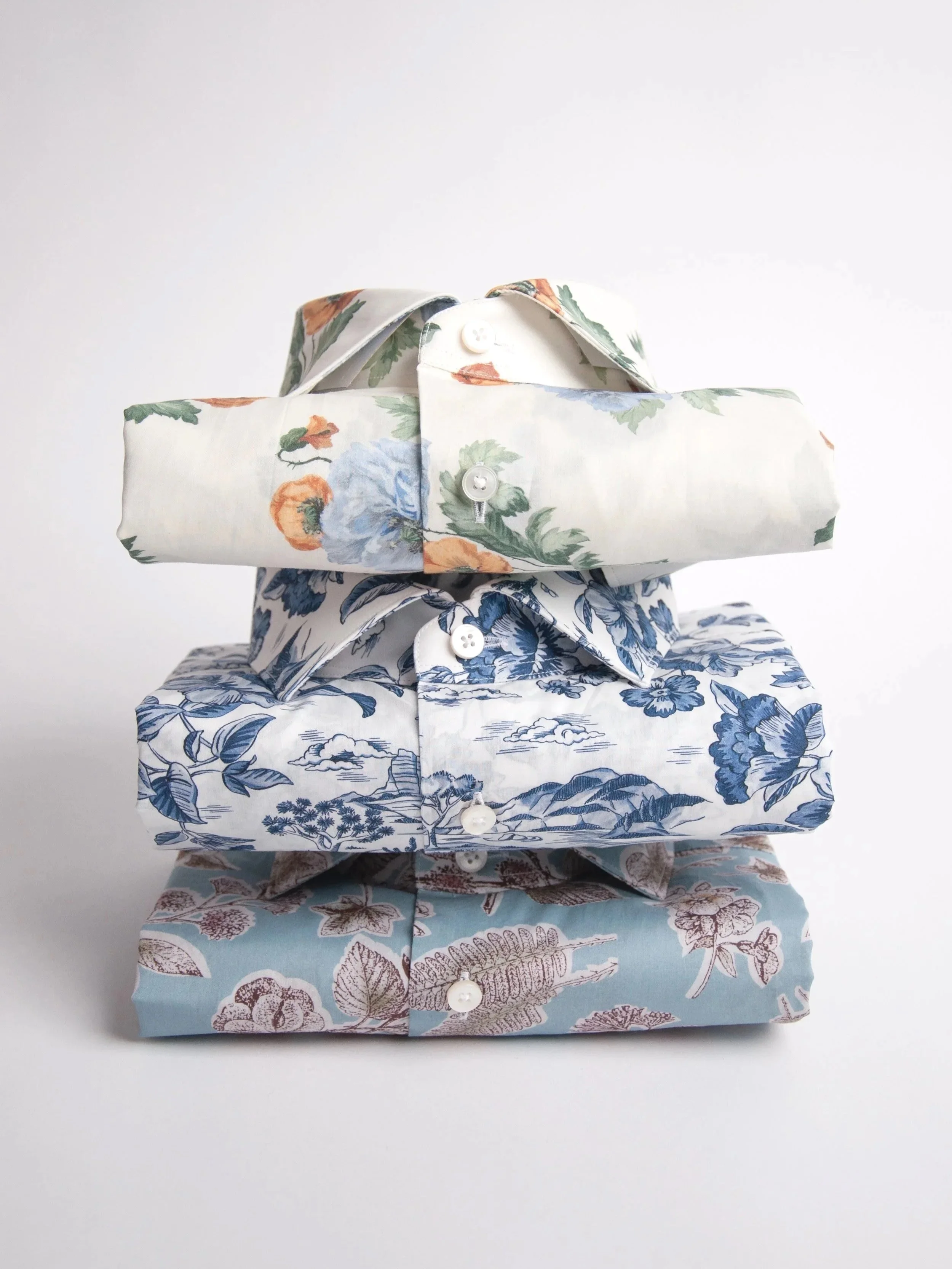 Stacked fabric boxes with different floral patterns, white buttons, and a white background.
