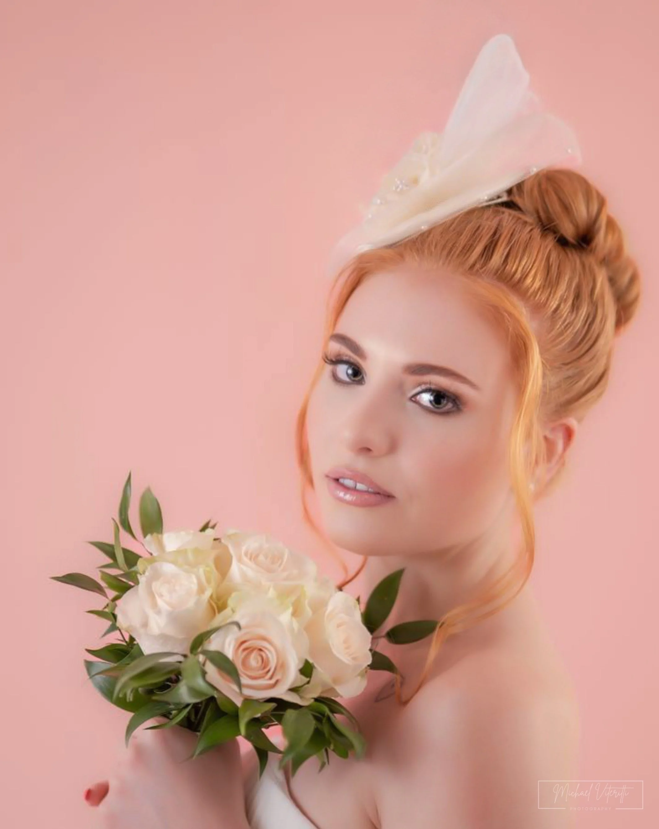 Ritratto di una donna con lunghi capelli rossi, che tiene un bouquet di fiori bianc i e rosa, con sfondo rosa, in uno stile artistico e raffinato.