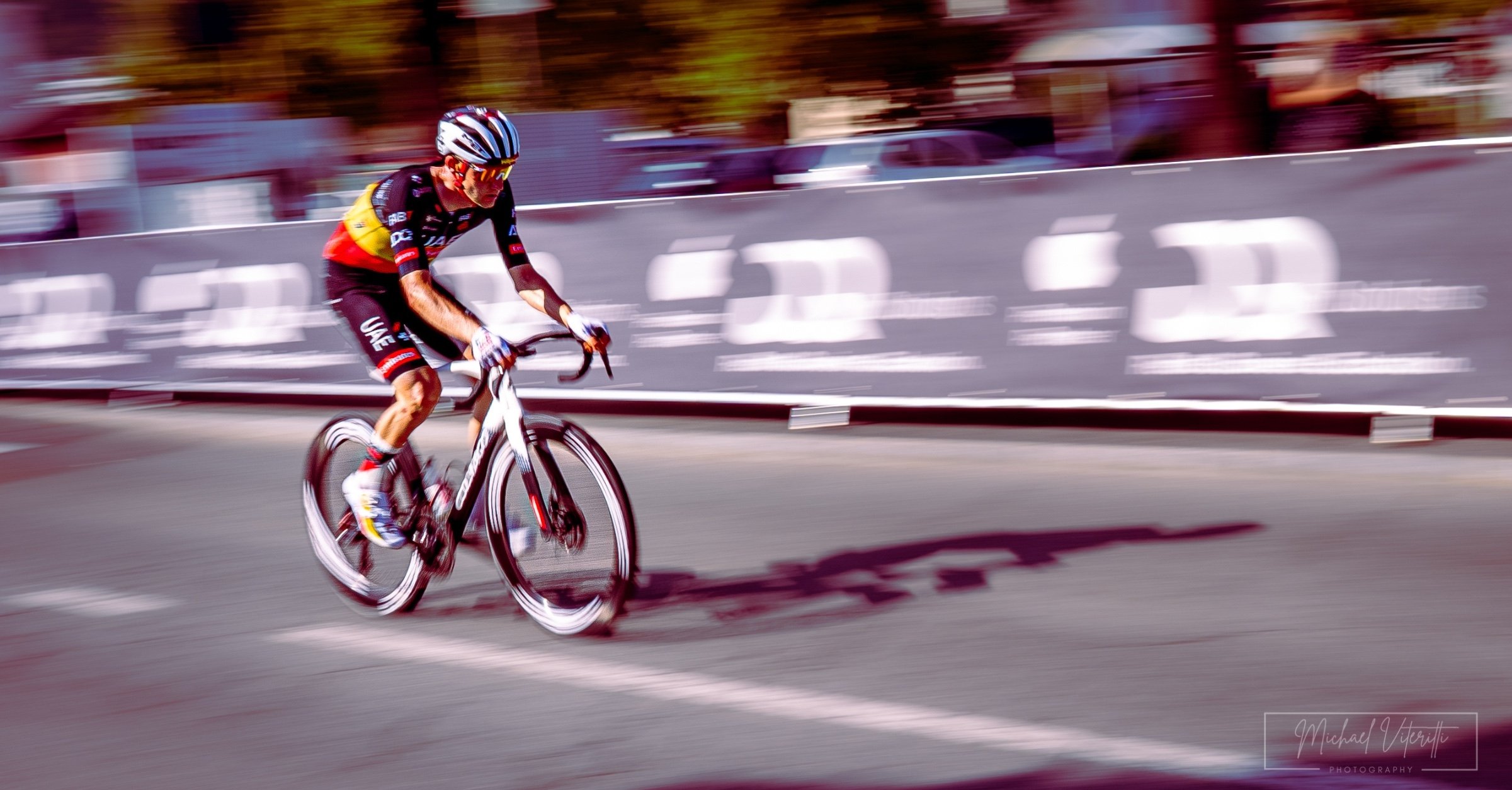 Ciclista che corre su strada durante una gara, con sfondo sfocato.