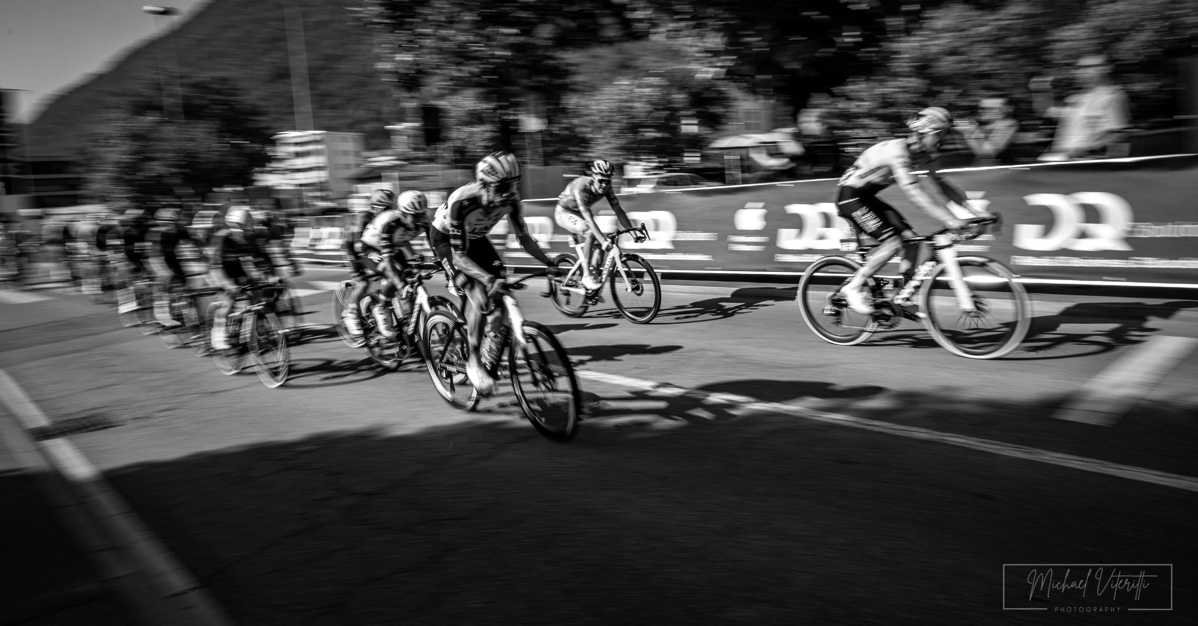 Gruppo di ciclisti che pedala in corsa, immagine in bianco e nero.