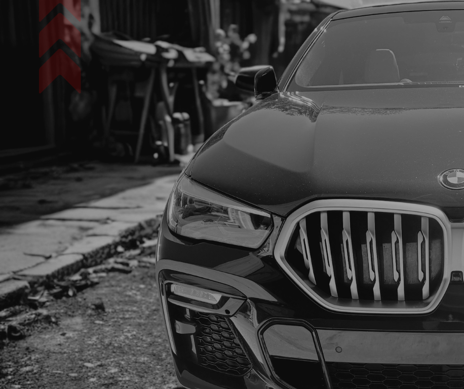 Close-up of the front of a black BMW car parked outdoors, showing the grille, headlight, and part of the hood.