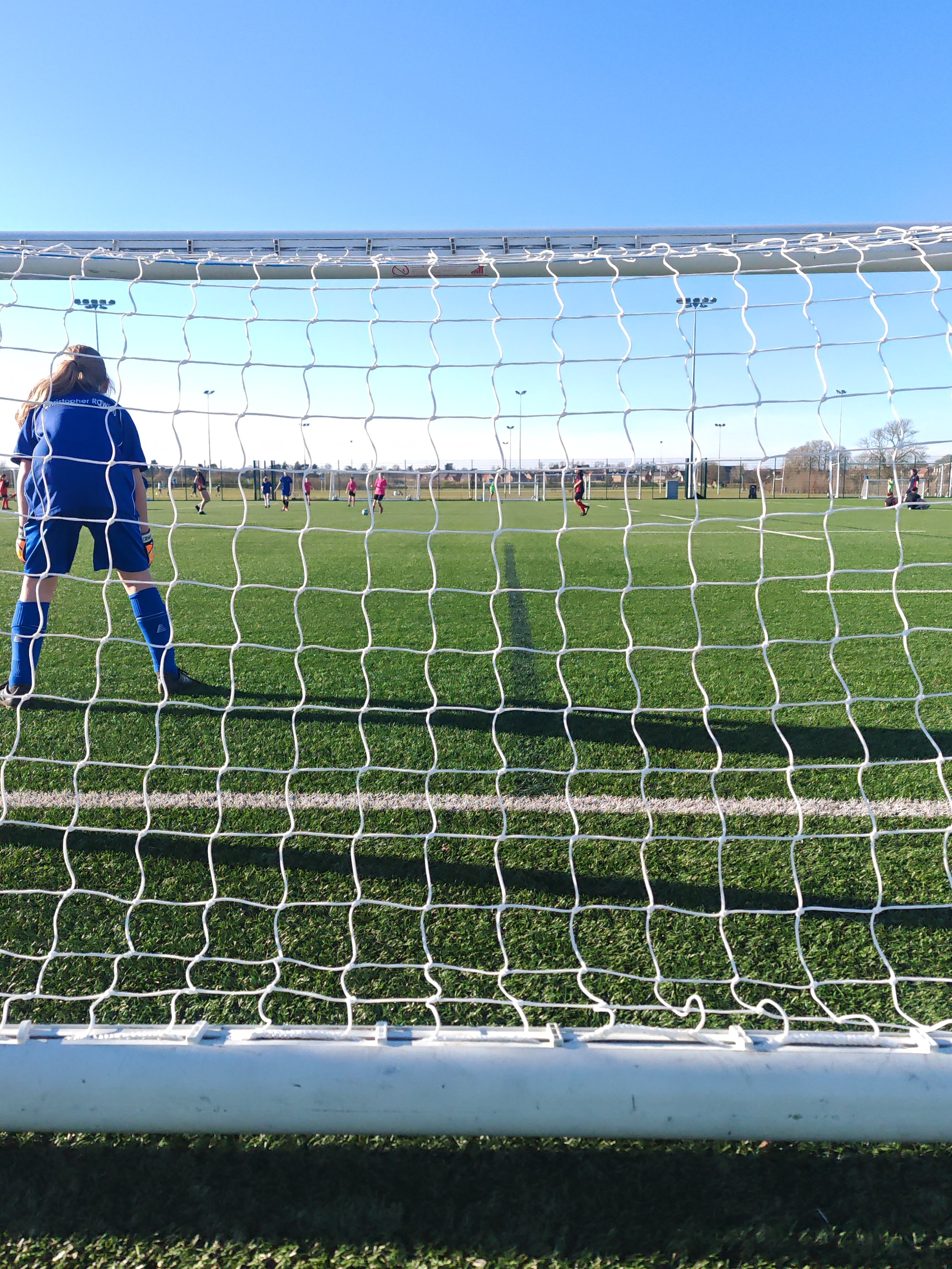 Football game with goalkeeper in the goal looking at players on the pitch