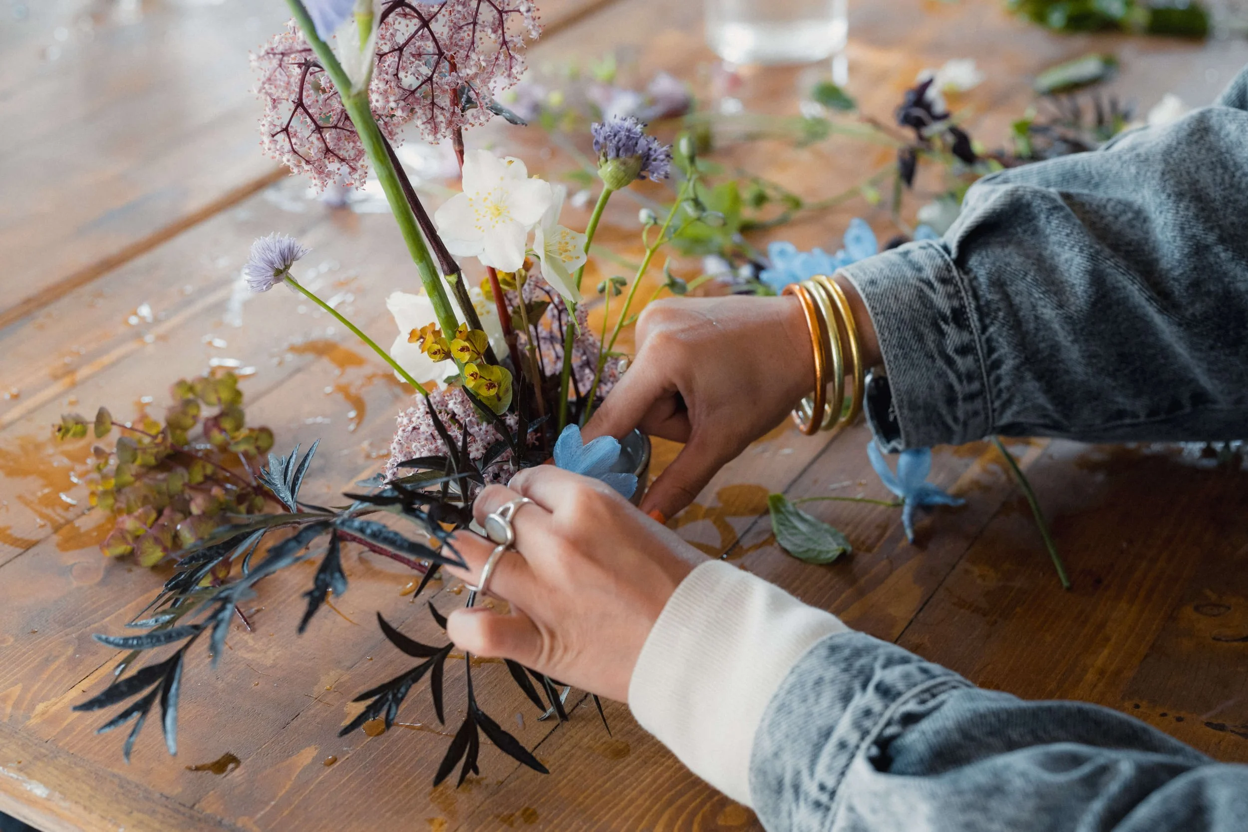 Mains en train de composer avec des fleurs du jardin pendant une formation fleuriste courte.