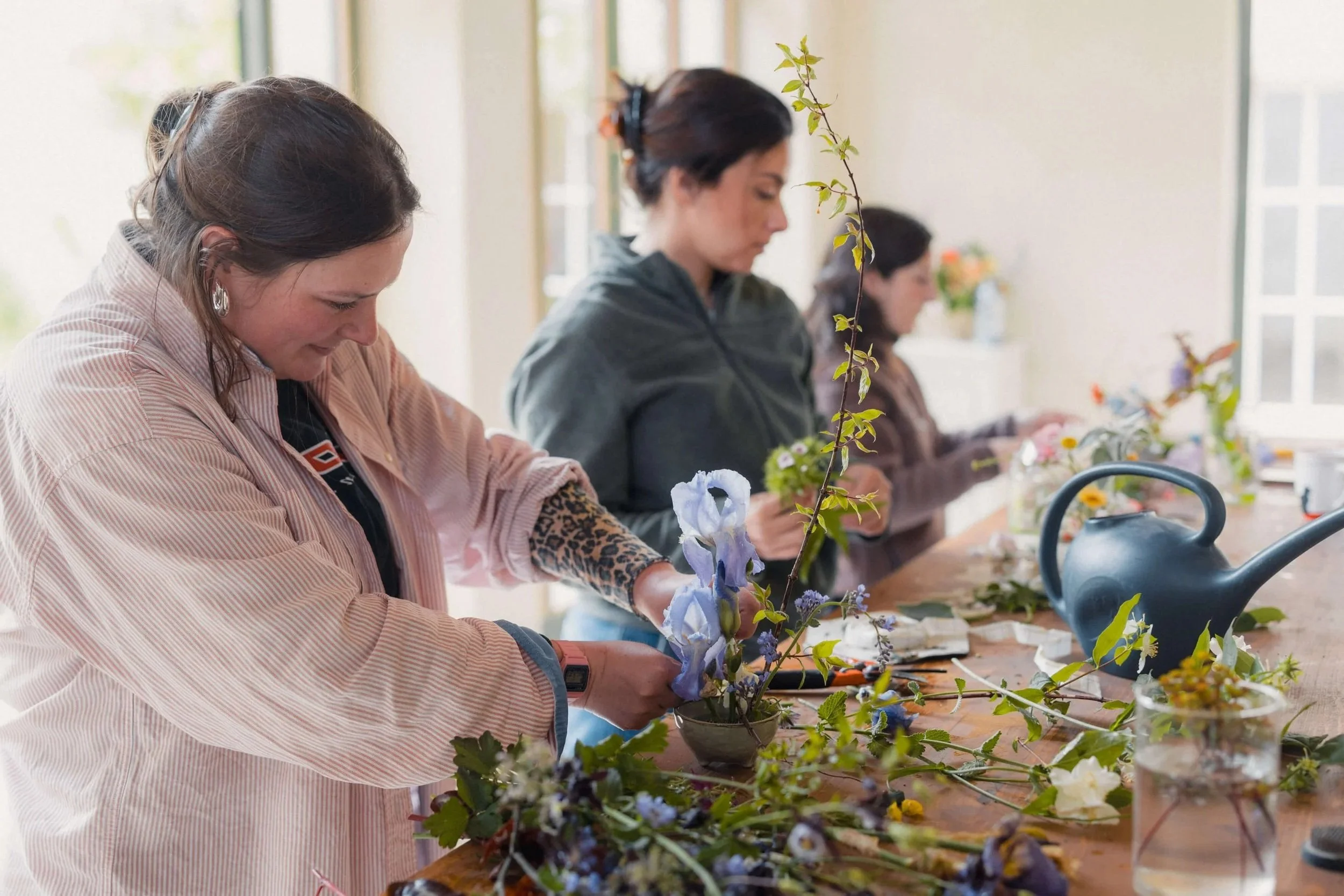 Participantes en train de composer avec les fleurs du jardin pendant un atelier floral résidentiel.