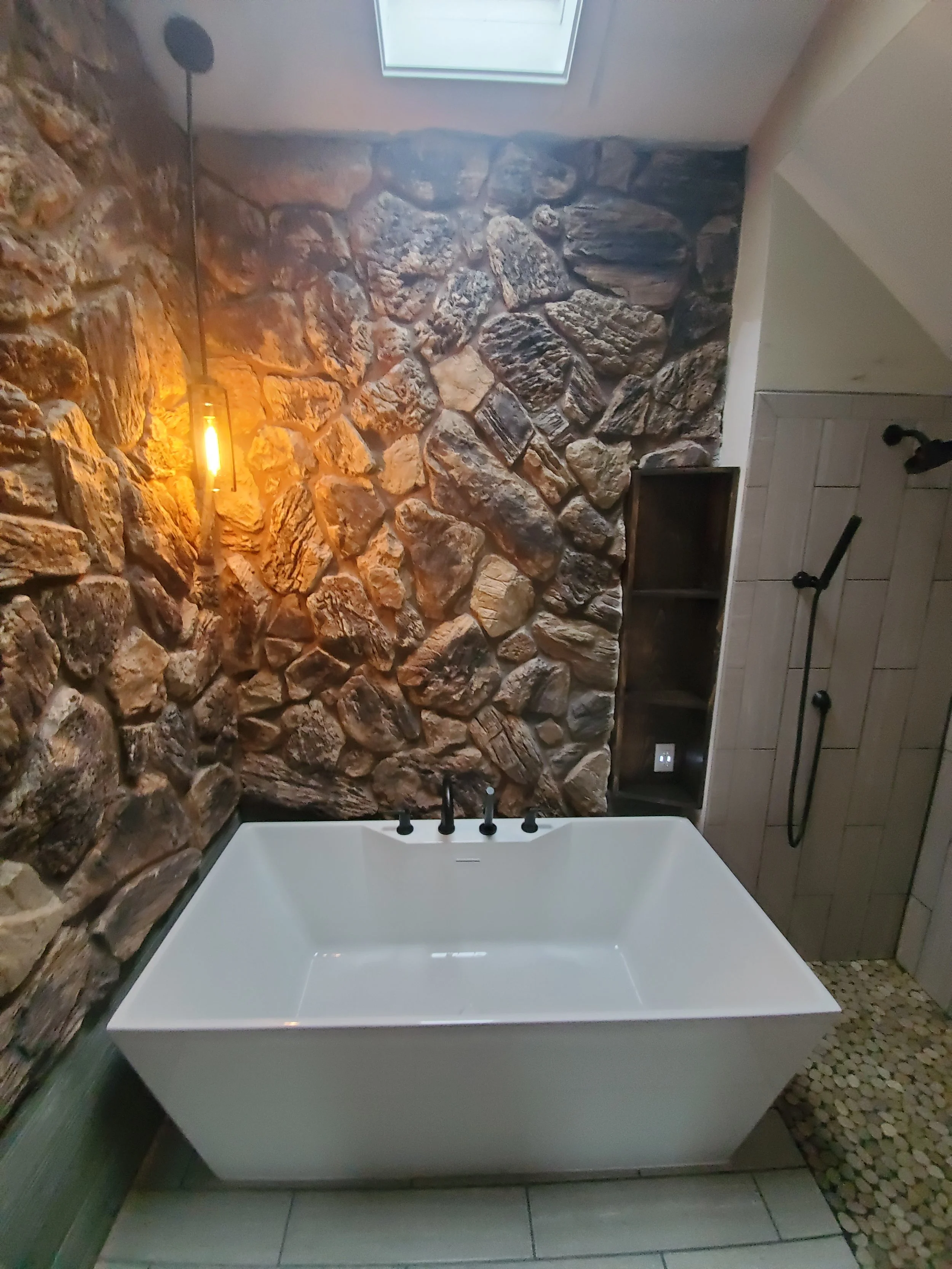 Luxury bathroom remodel with freestanding soaking tub and natural stone accent wall completed by Mr. H Remodel of middle Tennessee