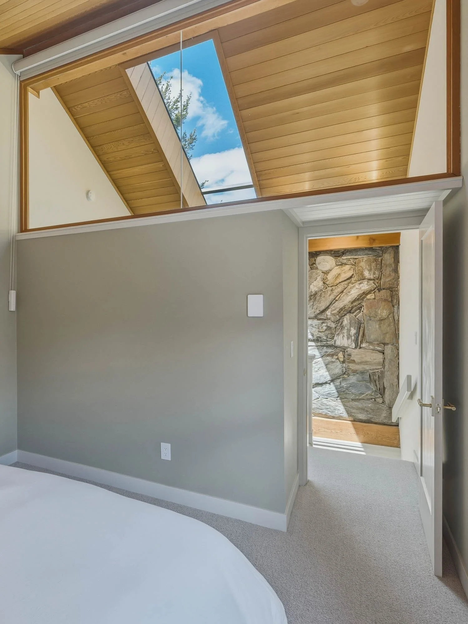 Architectural detail at 6117 Eagle Drive highlighting a sunlit vaulted wood plank ceiling, an overhead skylight, and clean modern finishes that optimize natural light.