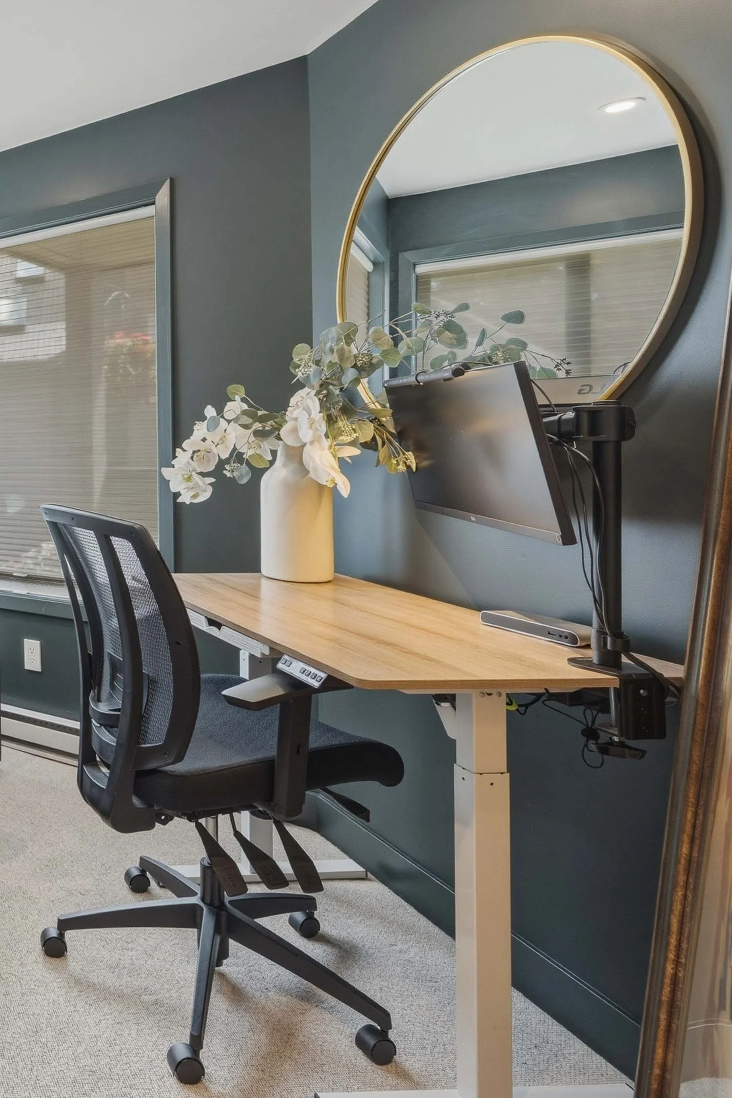 Dedicated home office setup in the second bedroom/office at 205-6117 Eagle Drive, showing a sleek workstation layout with adjustable monitor arm and window treatments.
