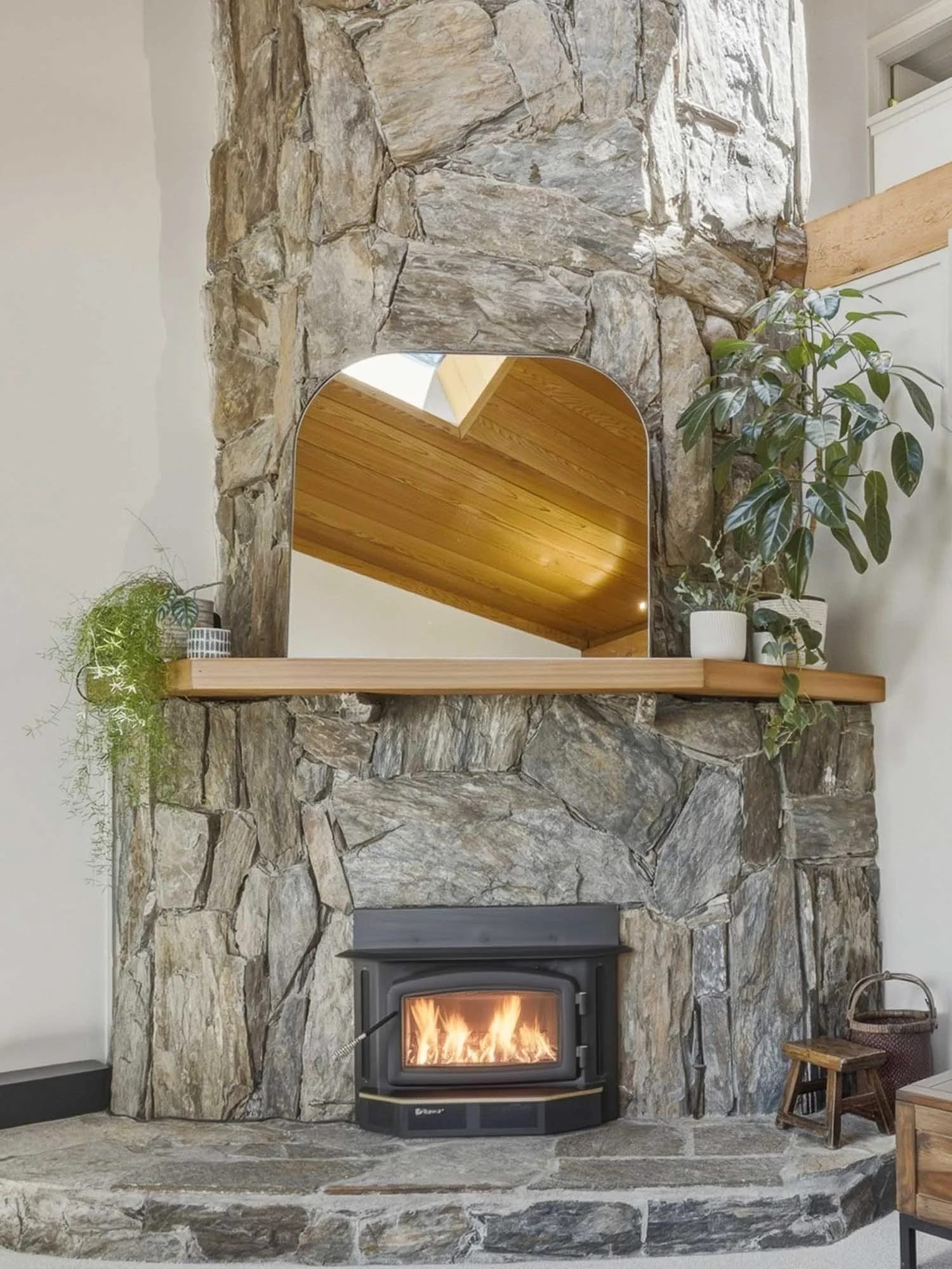 A crackling fire inside the premium Regency wood-burning fireplace at 6117 Eagle Drive, featuring a floor-to-ceiling stone surround, natural wood mantel, and cozy alpine ambiance.