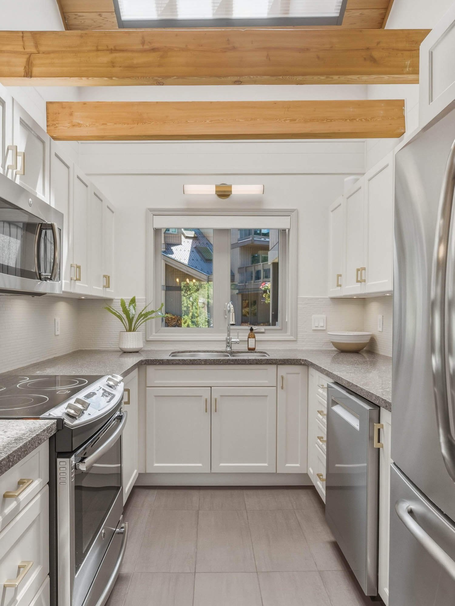 Modern kitchen inside this Whistler 2-bedroom townhouse for sale, highlighting bright white shaker cabinets, premium stainless steel appliances, a Bosch dishwasher, and ample counter space.