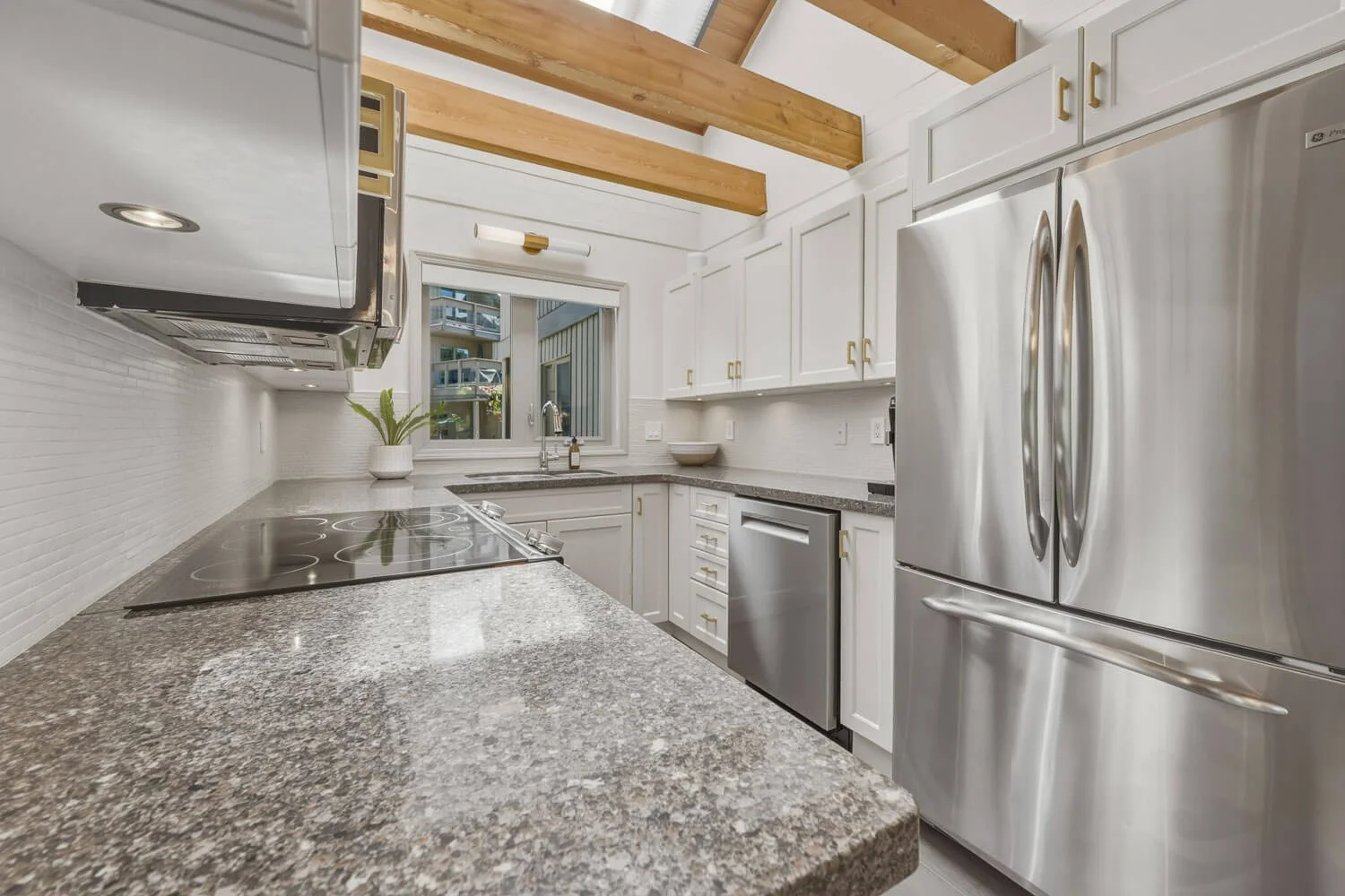 The updated kitchen features stone countertops, stainless steel appliances, and heated tile floors, plus a large skylight with automated Hunter Douglas window shade