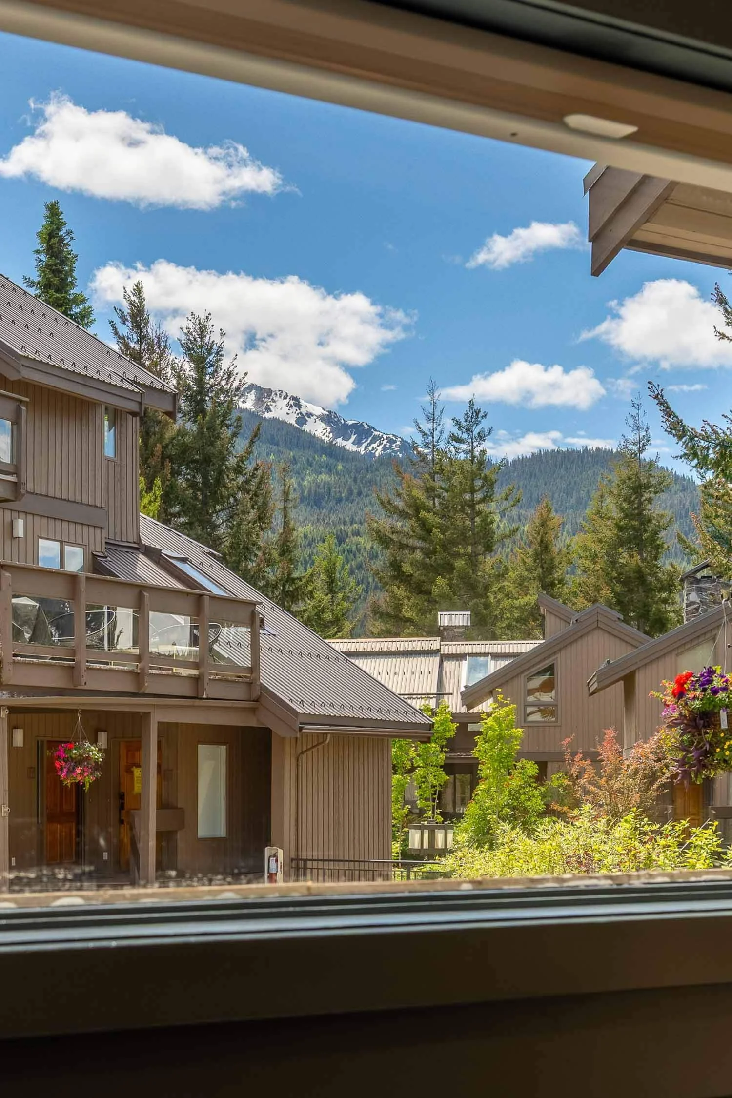 Mountain-view exterior architecture of the Sunrise Eagle Drive complex surrounded by evergreens, showcasing a premium Whistler Cay Heights townhouse for sale under a blue sky.