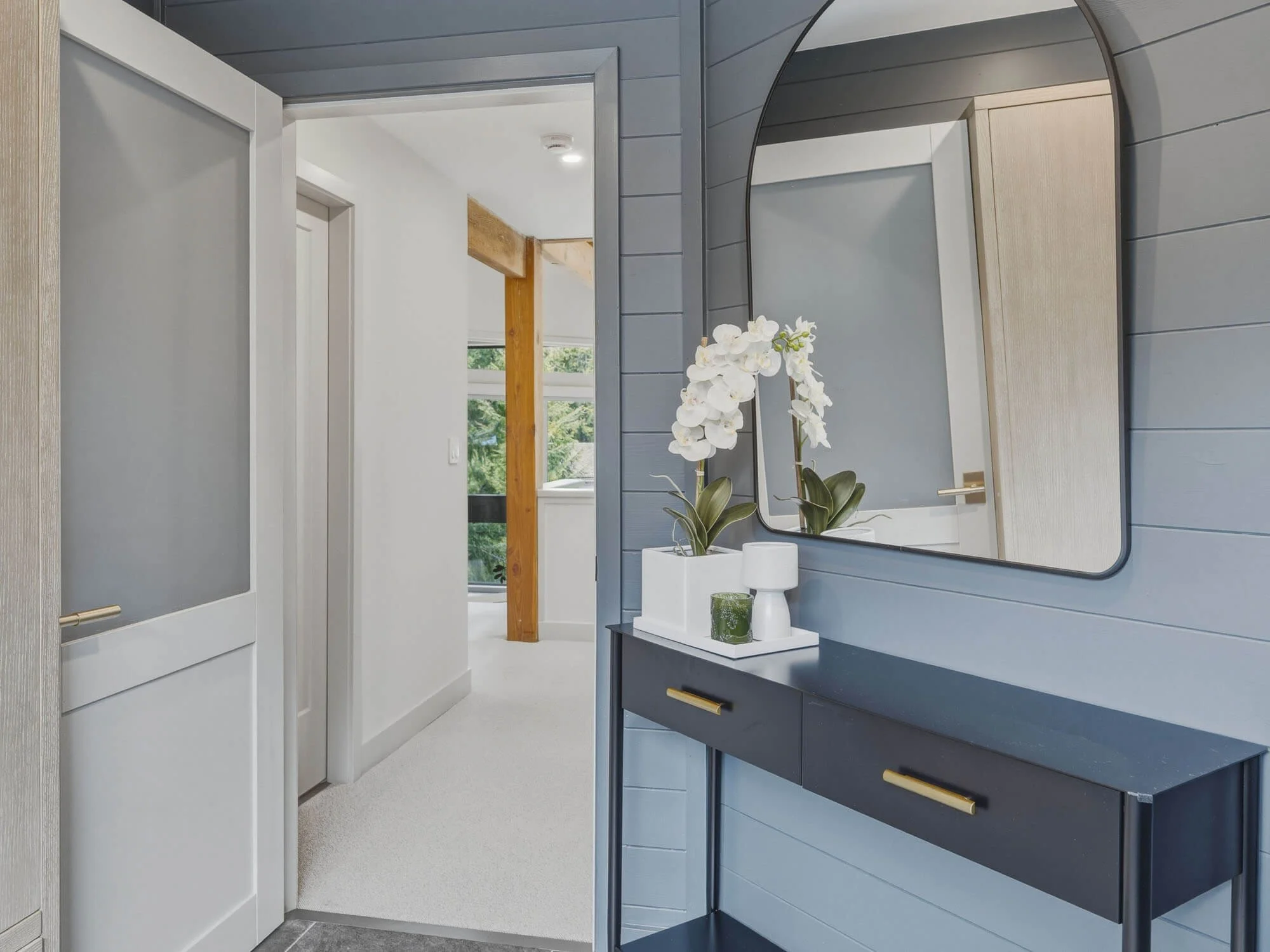 Luxury mudroom and front entry in this Whistler Cay Heights townhouse for sale, showing a dark console table, large mirror, and seamless transition to the main hallway and living areas.