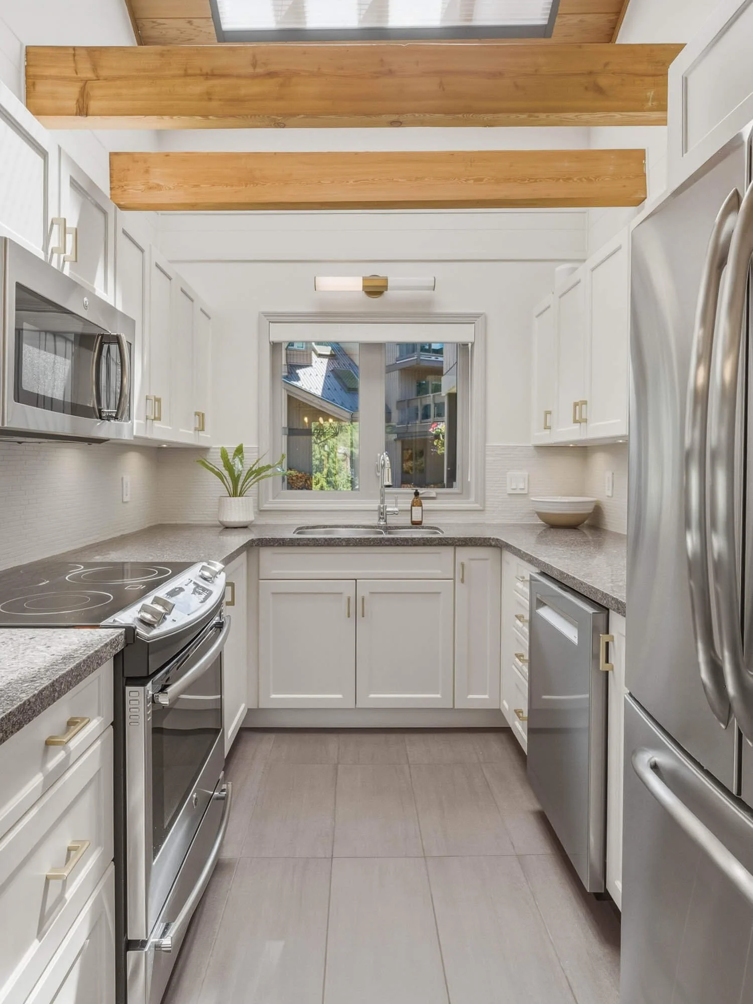 Elegant kitchen workspace at 6117 Eagle Drive showcasing white shaker cabinets, a window above the sink with natural light, and clean lines under a warm wood-panelled ceiling.