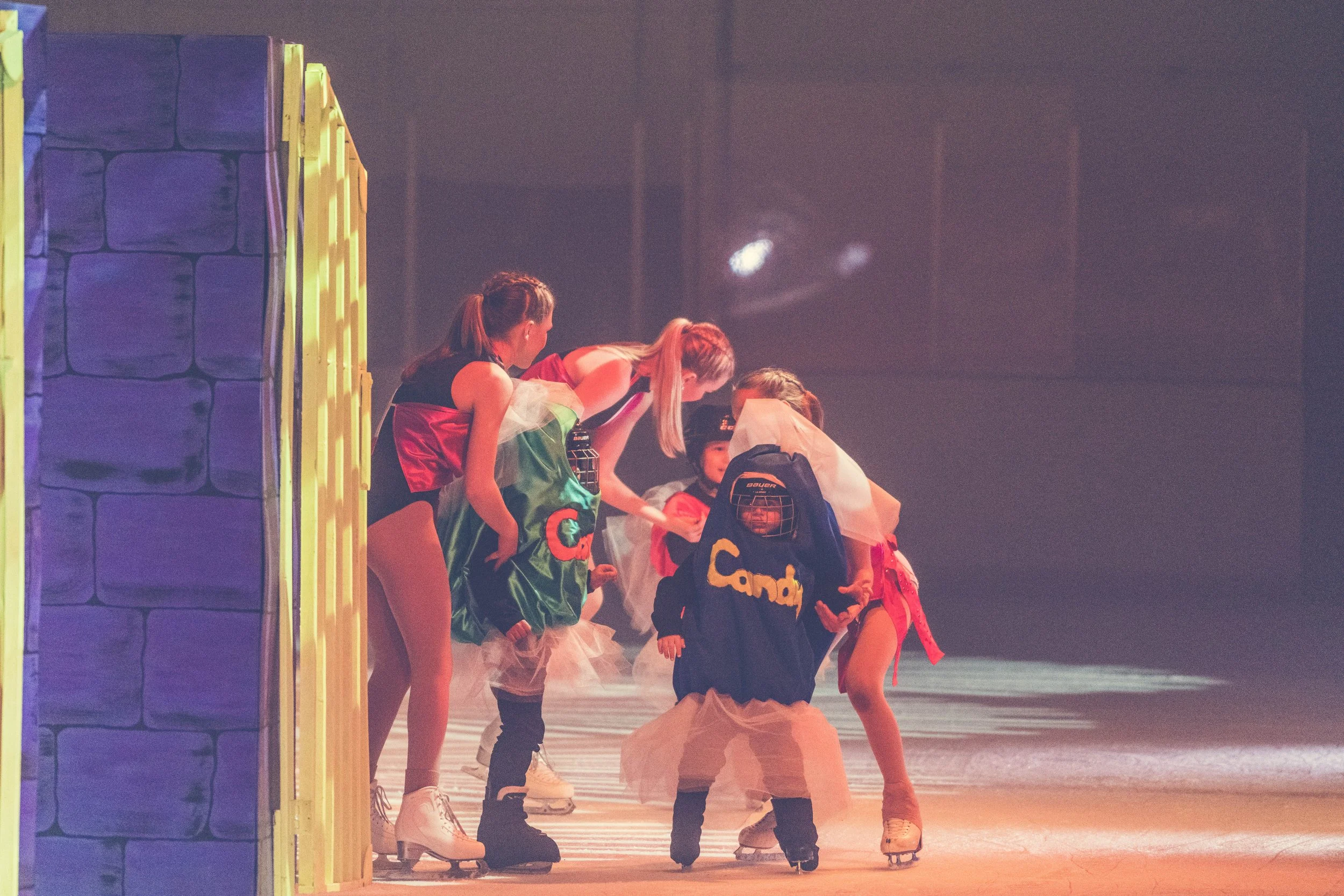 Group of children in costumes on an ice skating rink.
