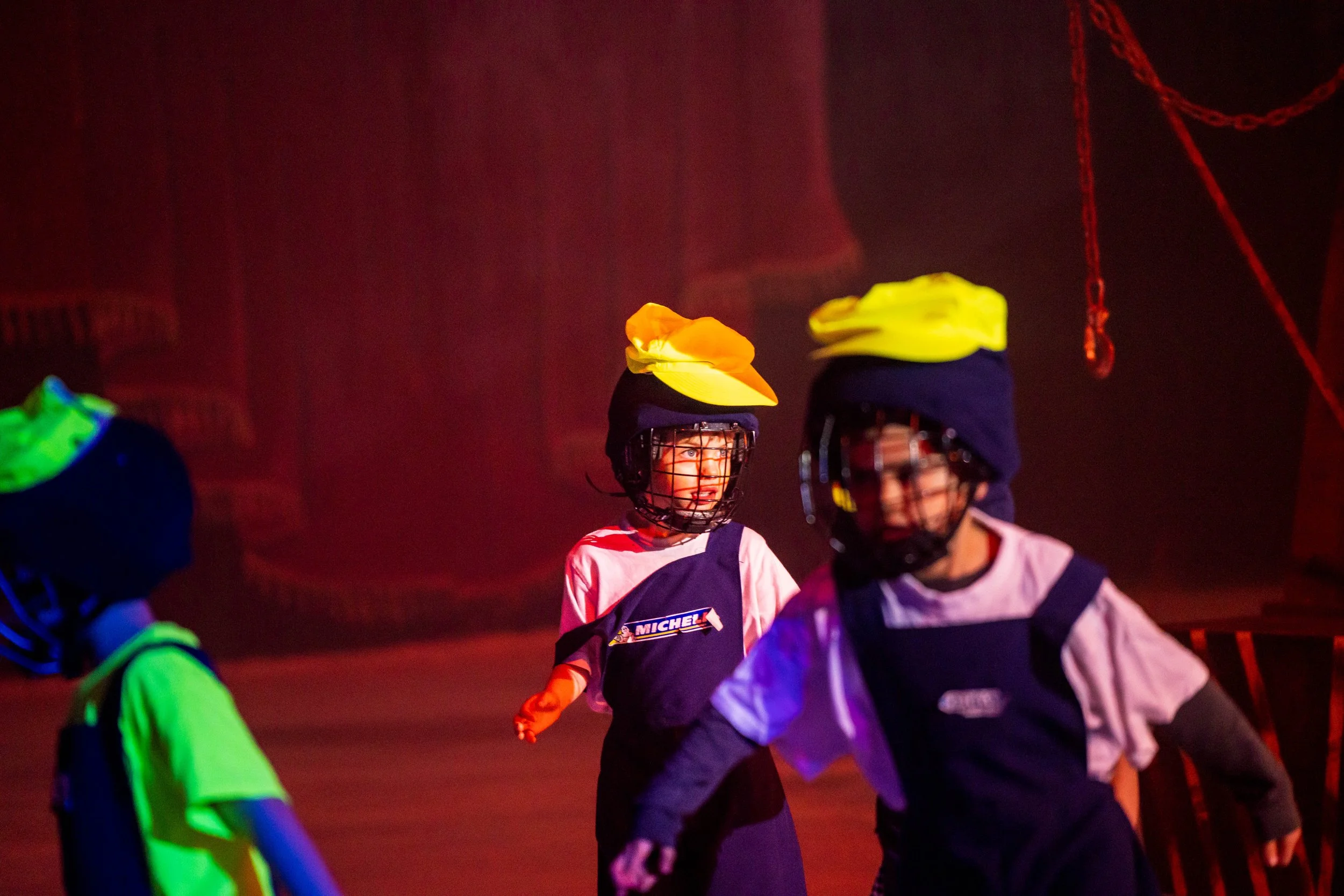 Hockey players wearing colorful uniforms and protective helmets during a game or practice, illuminated by vibrant, possibly stage or arena lighting.