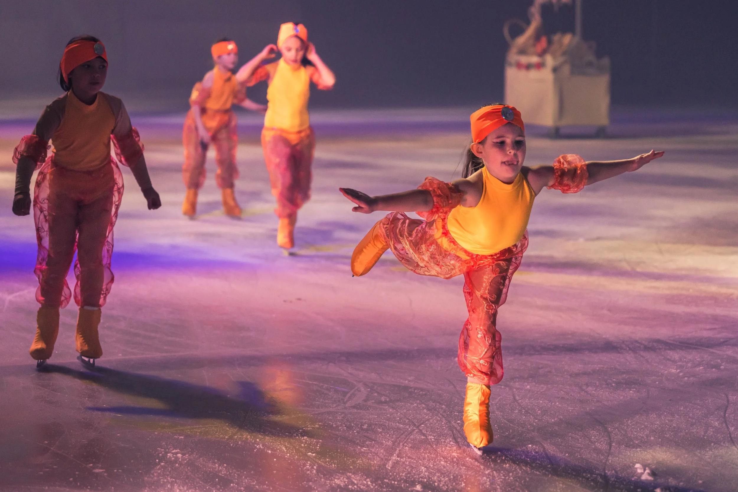 Children in yellow costumes ice skating.