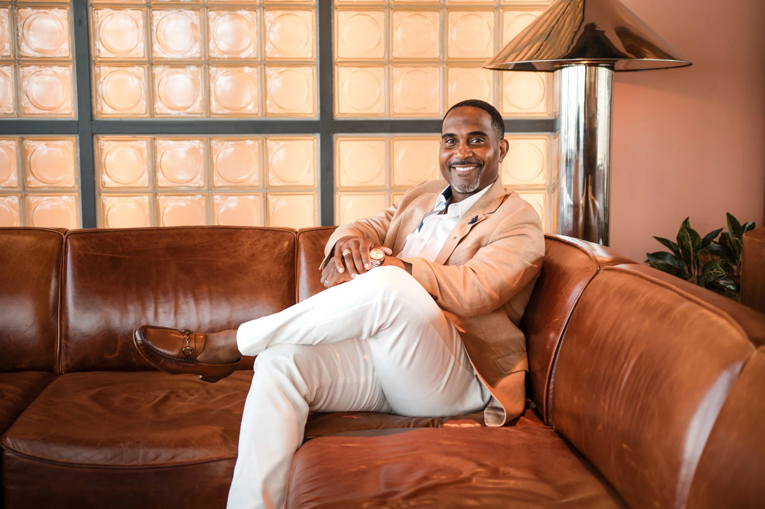 Randall Frazier, Founder and Owner of Silverback Hospitality, smiling in a blazer, seated in a leather lounge.