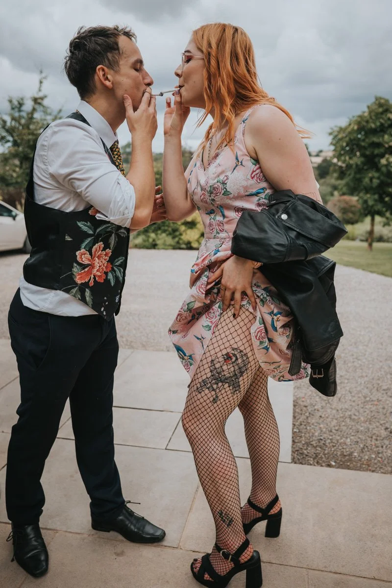 A man and a woman are sharing an intimate moment outside, with the man gently touching the woman's face while they lean in close, about to kiss.