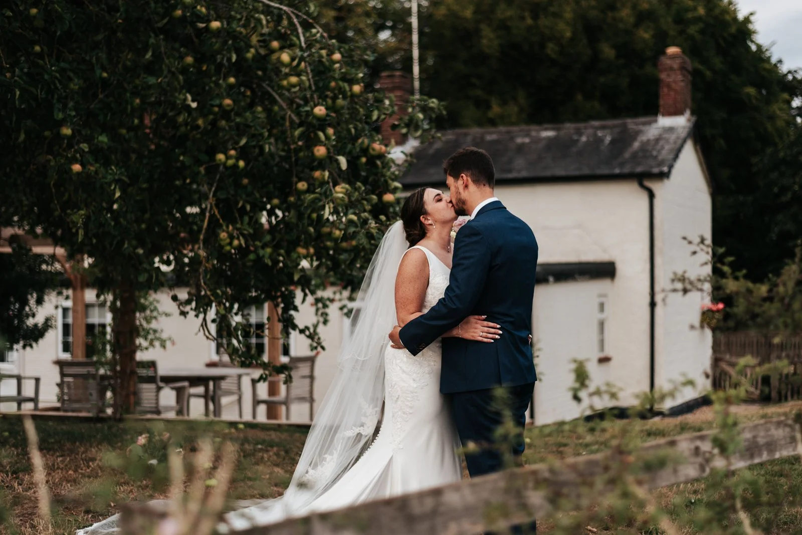 A bride and groom kiss outdoors during their wedding, at Granary Estates near Newmarket.