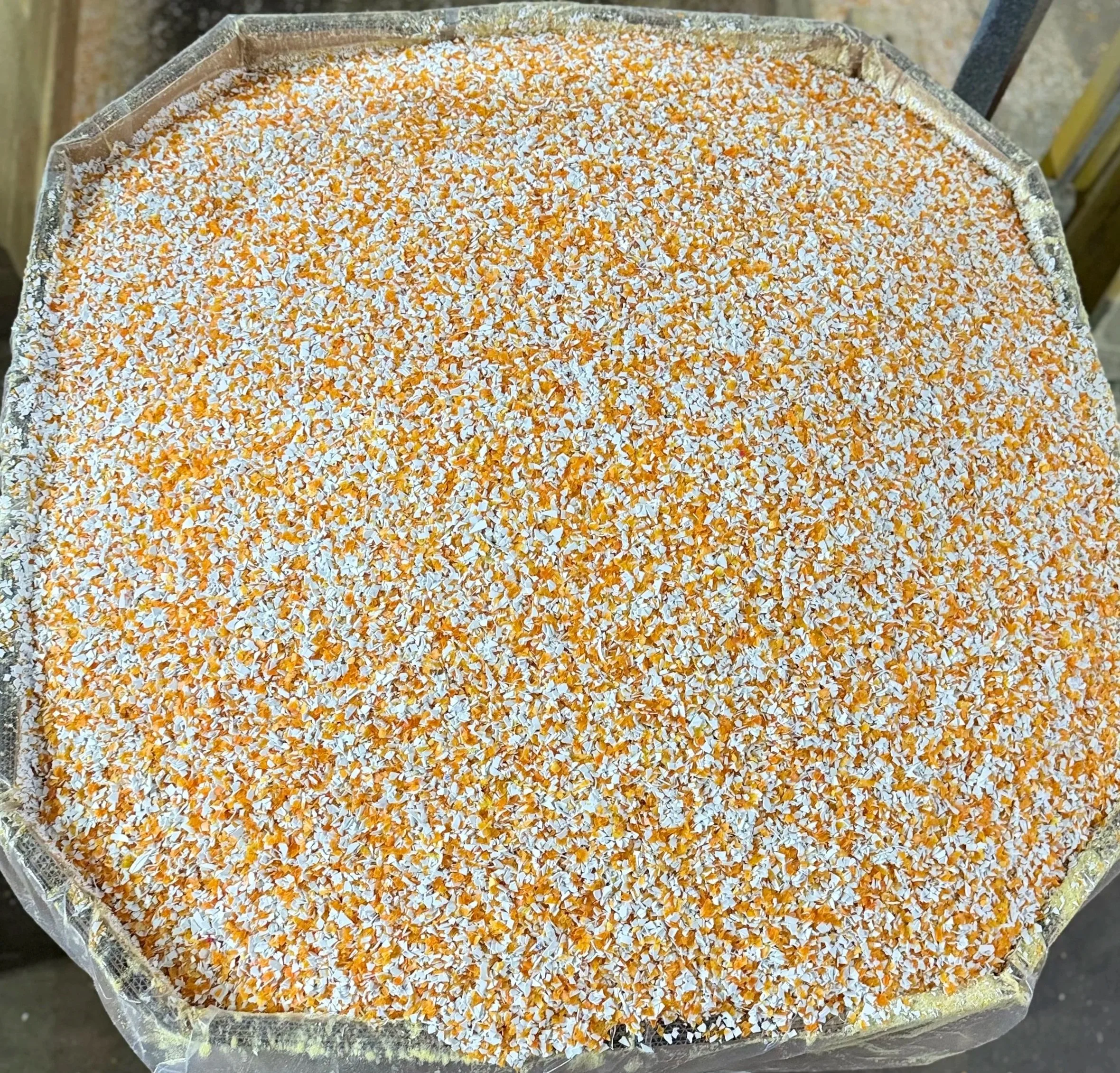 Close-up of a box filled with small pieces of orange and white regrind.