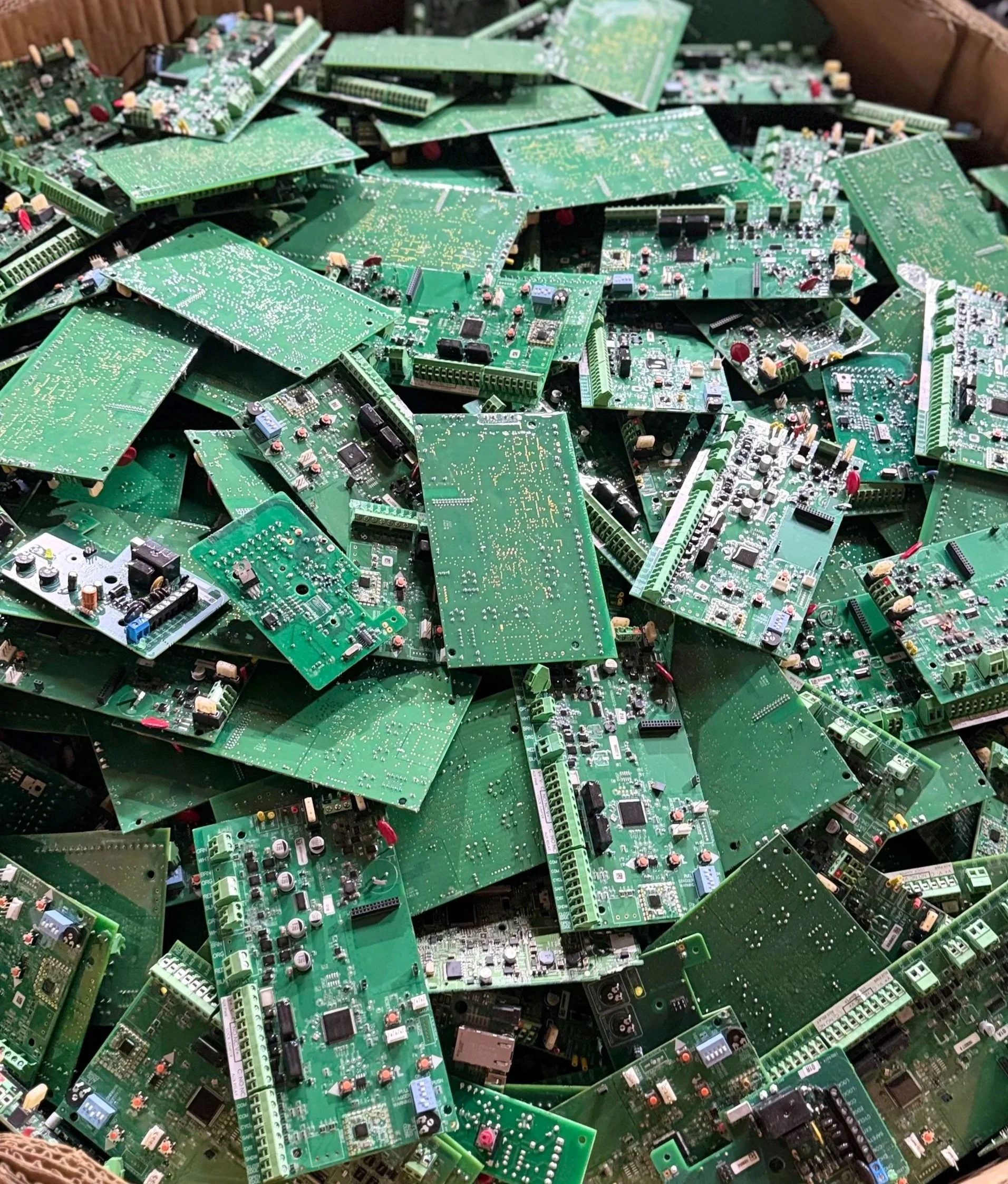 Pile of green printed circuit boards (PCBs) with various electronic components.