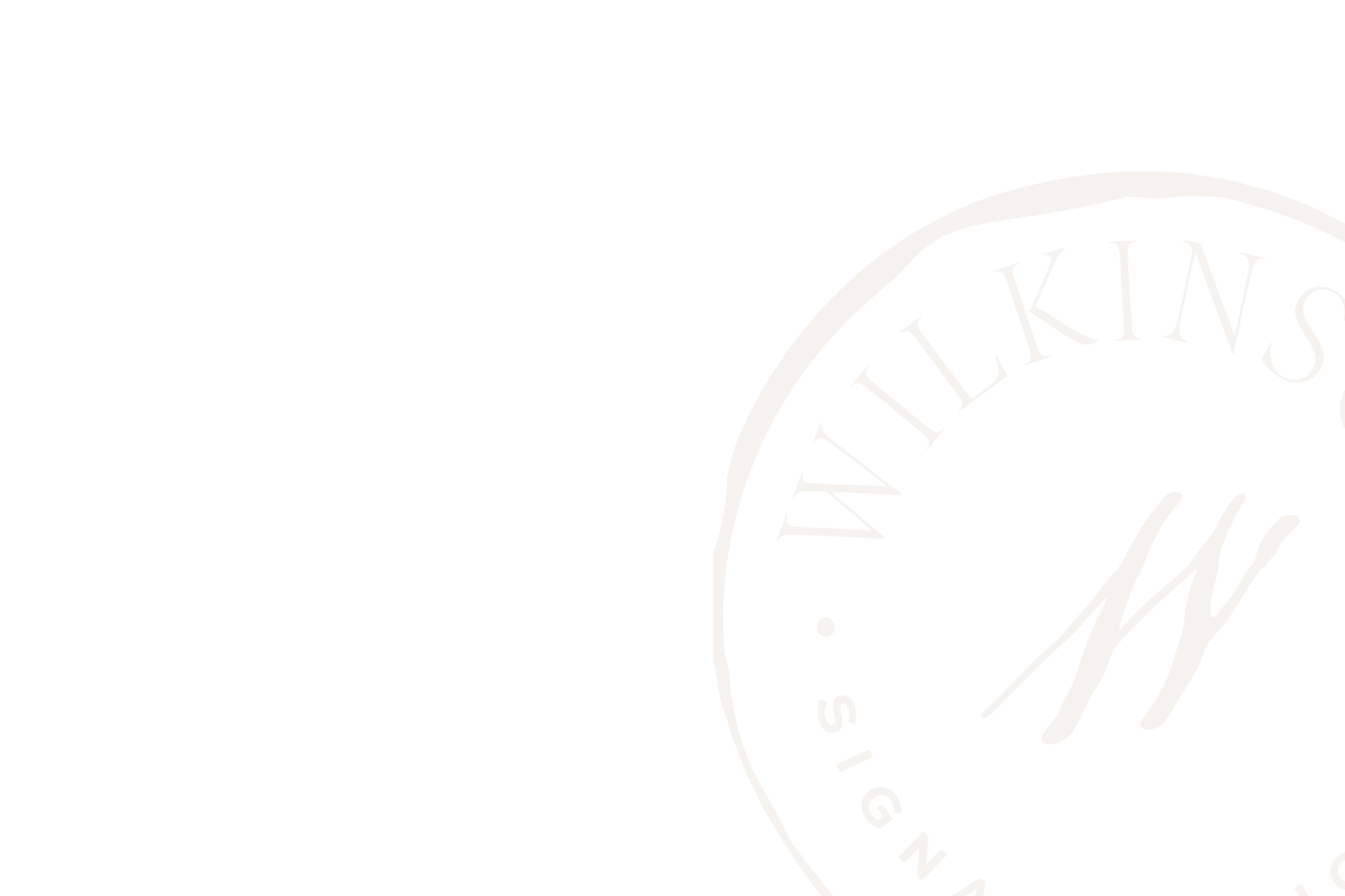 Close-up of a circular logo with the word "WILKINGS" on the upper arc and part of a handwritten "N" on the lower part, all in beige color on a black background.