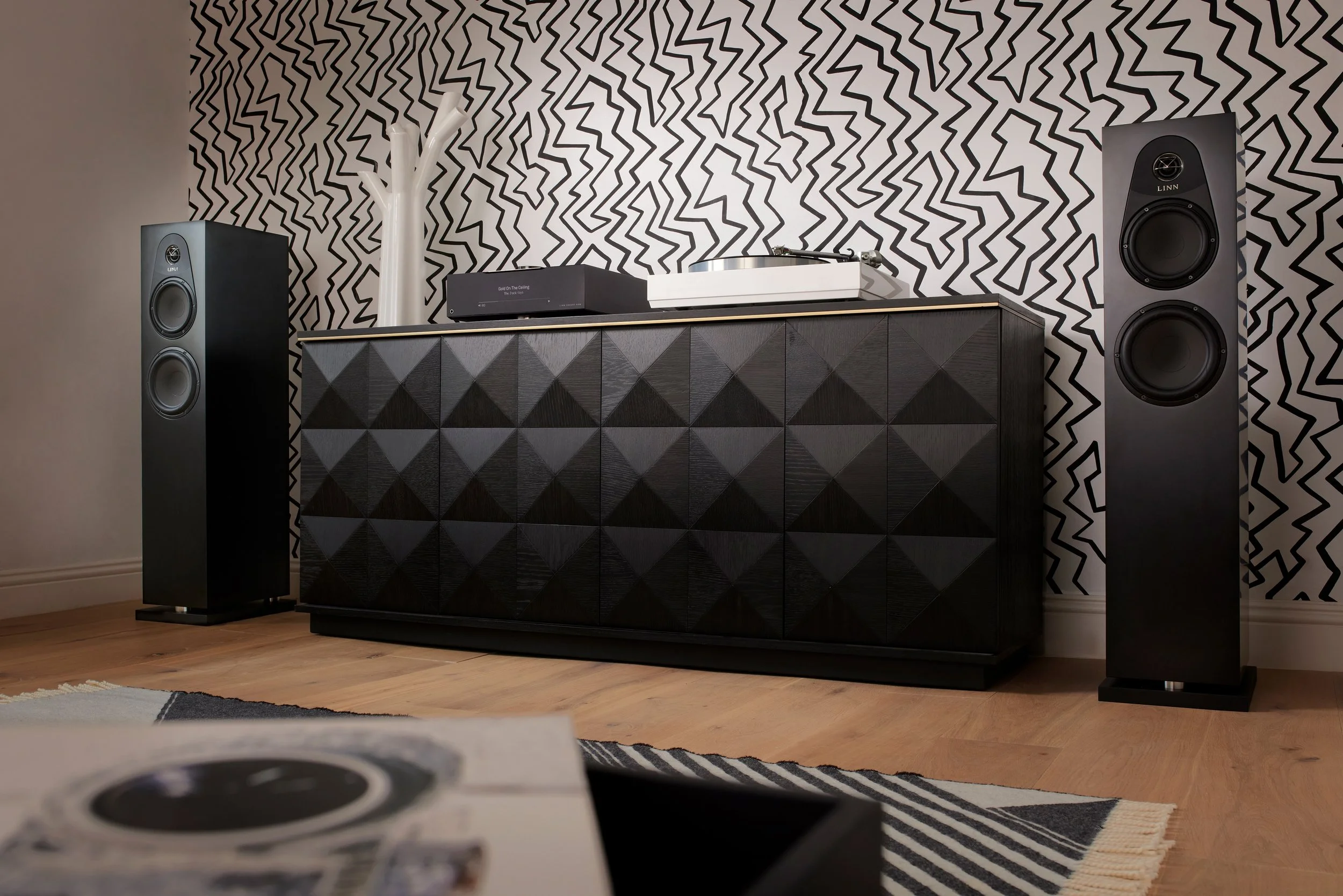 Coppia di diffusori Linn 150 in finitura Satin Black con Selekt DSM Classic Hub e giradischi, integrata in un soggiorno contemporaneo.