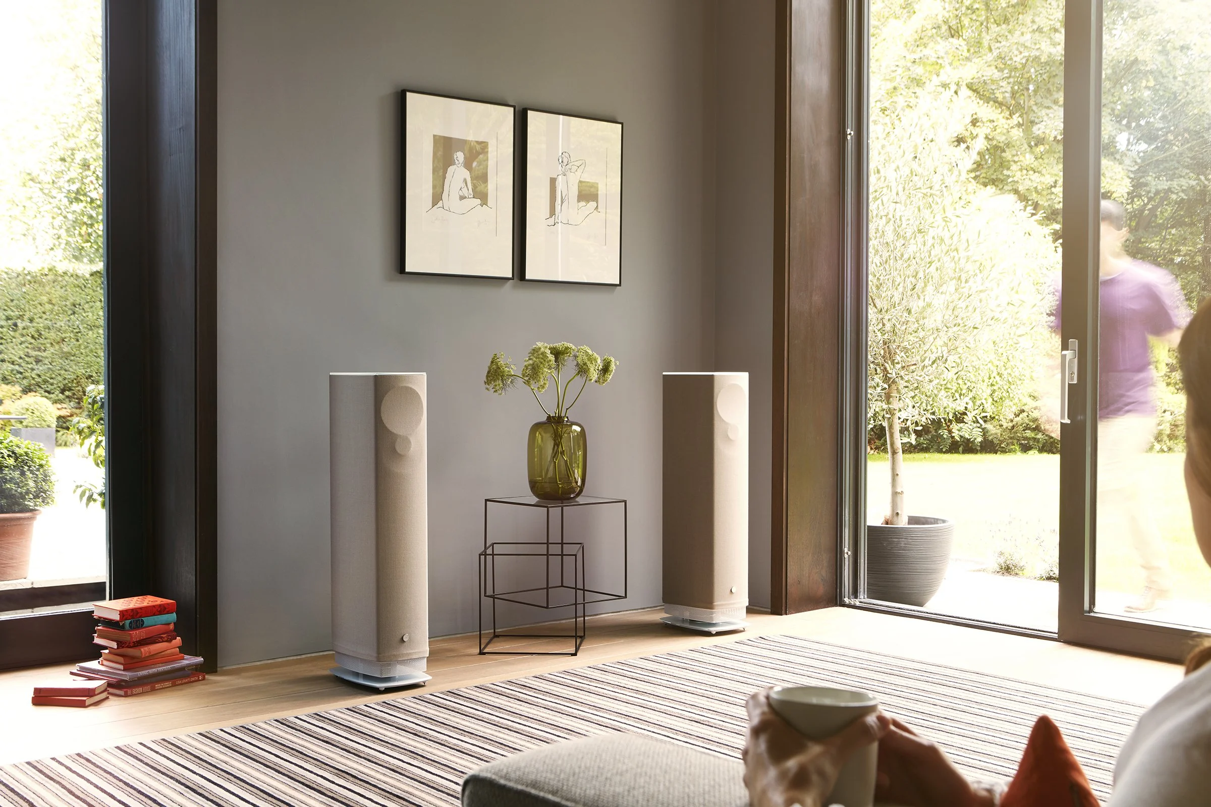 Coppia di diffusori attivi Linn 530 in finitura Butterscotch con base bianca, collocata in un soggiorno luminoso affacciato sul giardino.