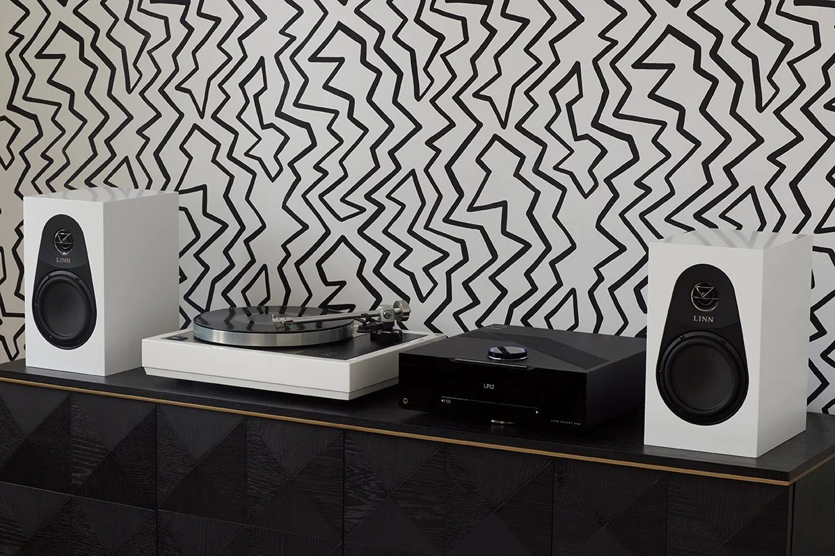 Setup audio Linn con due casse bianche, un giradischi LP12 e un DSM Linn su un mobile nero con finitura a triangoli