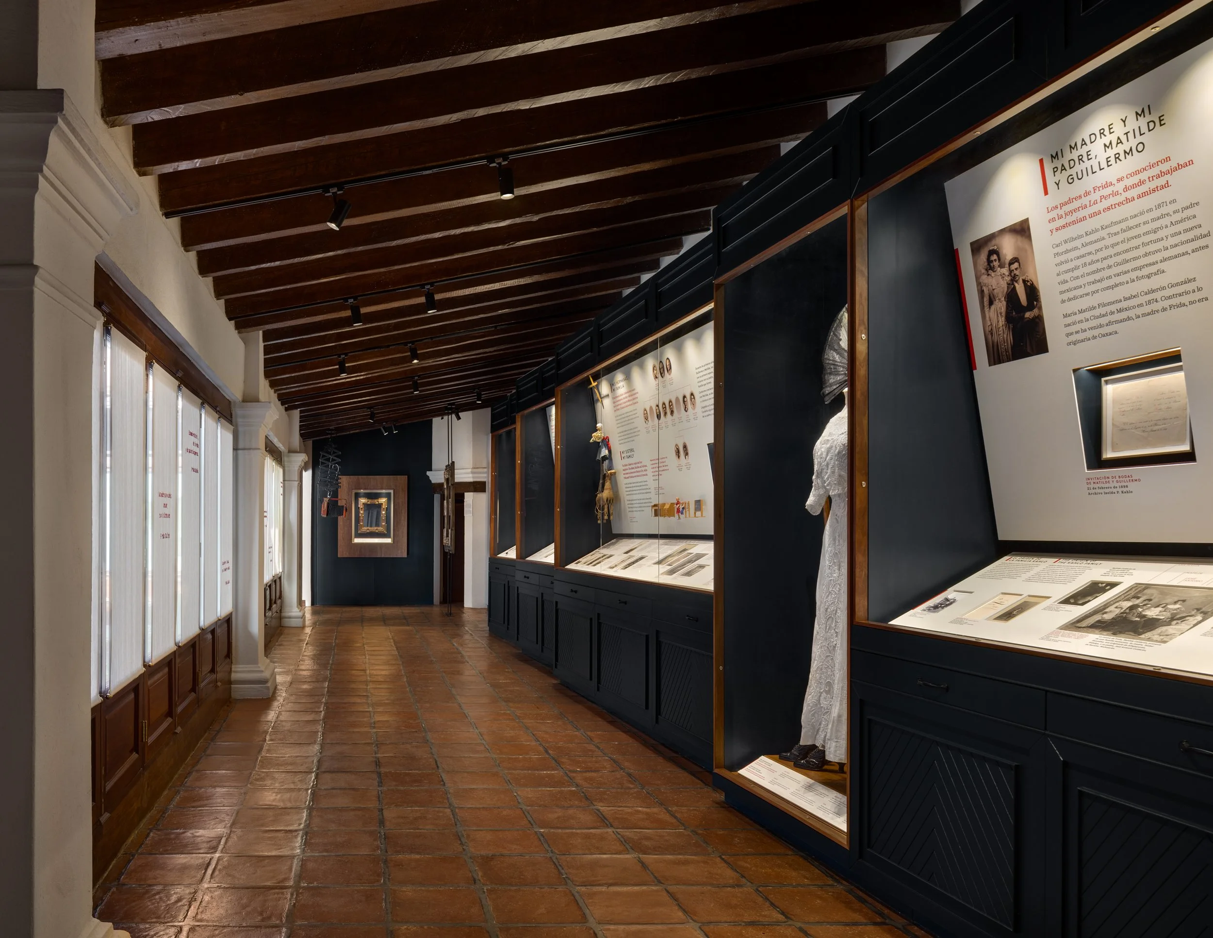 Interior of a museum with display cases, informational posters, wooden ceiling beams, and natural light coming through windows.