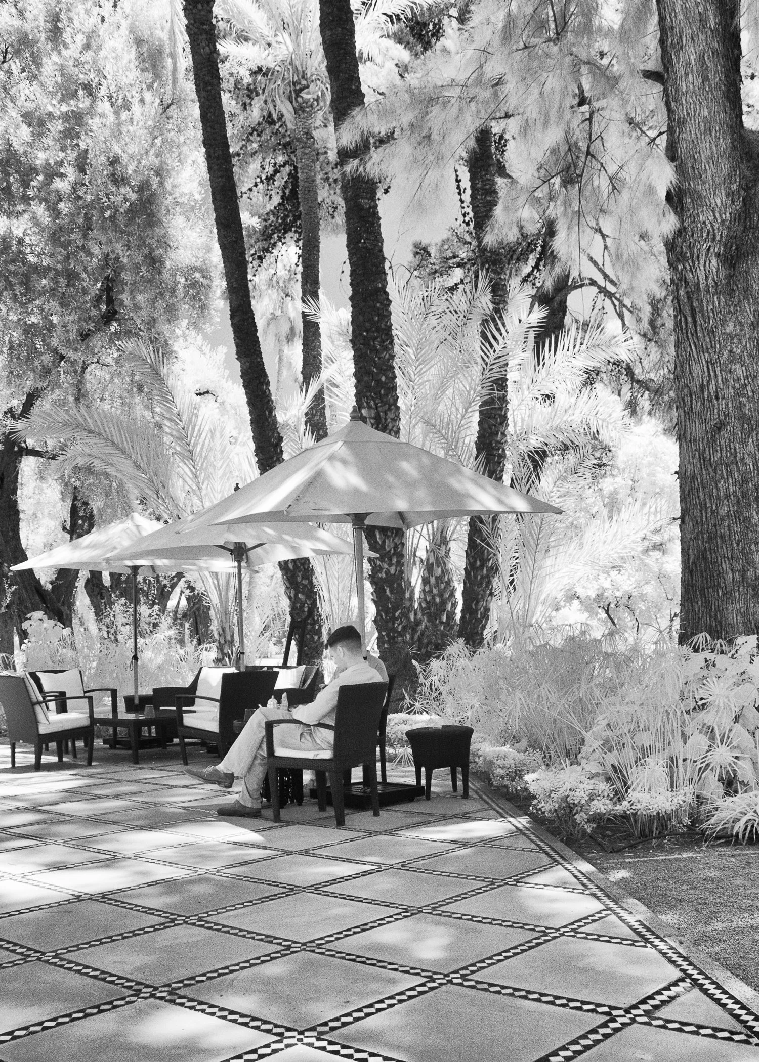 Infrared- "Hotel Umbrellas, Marrakech" Patio of Tables. Man. Reading. Morocco.