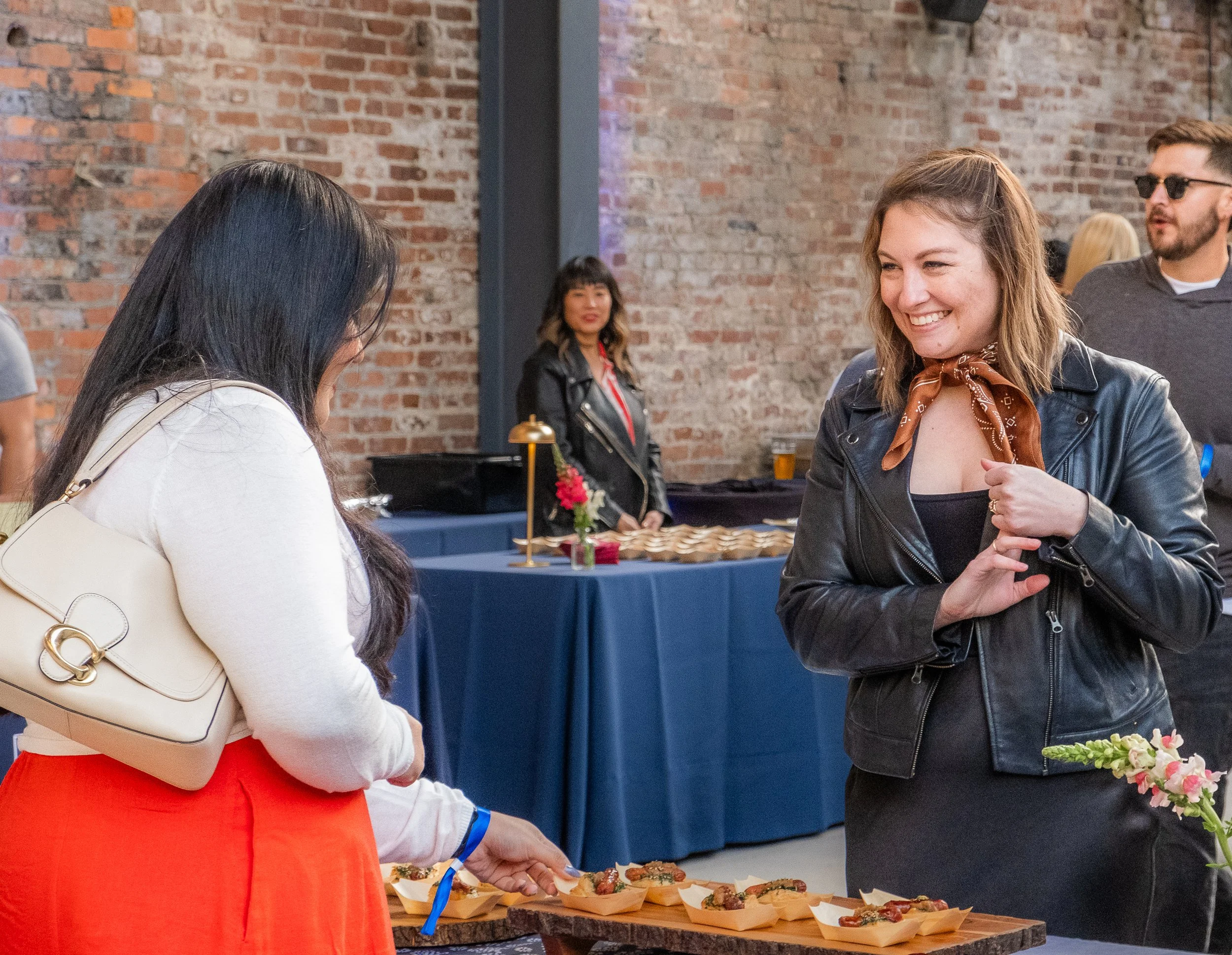 Nashville marketing professional Jordan Farrell smiling at a guest while they chat at a table of food at Les Dames Nashville's spring event Le Fete De Dames