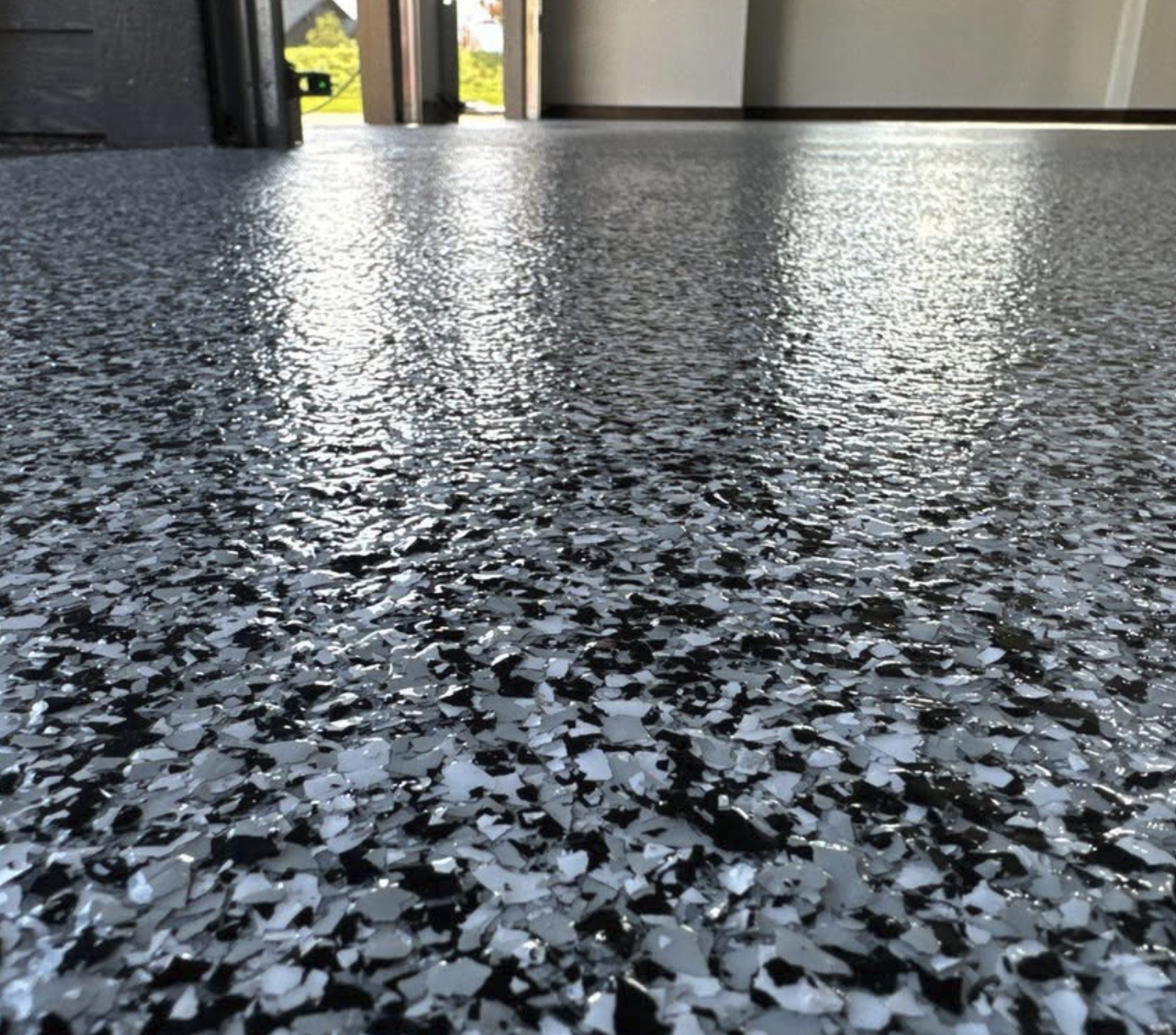 Close-up of a decorative black and white terrazzo floor inside a building with a doorway and windows in the background.