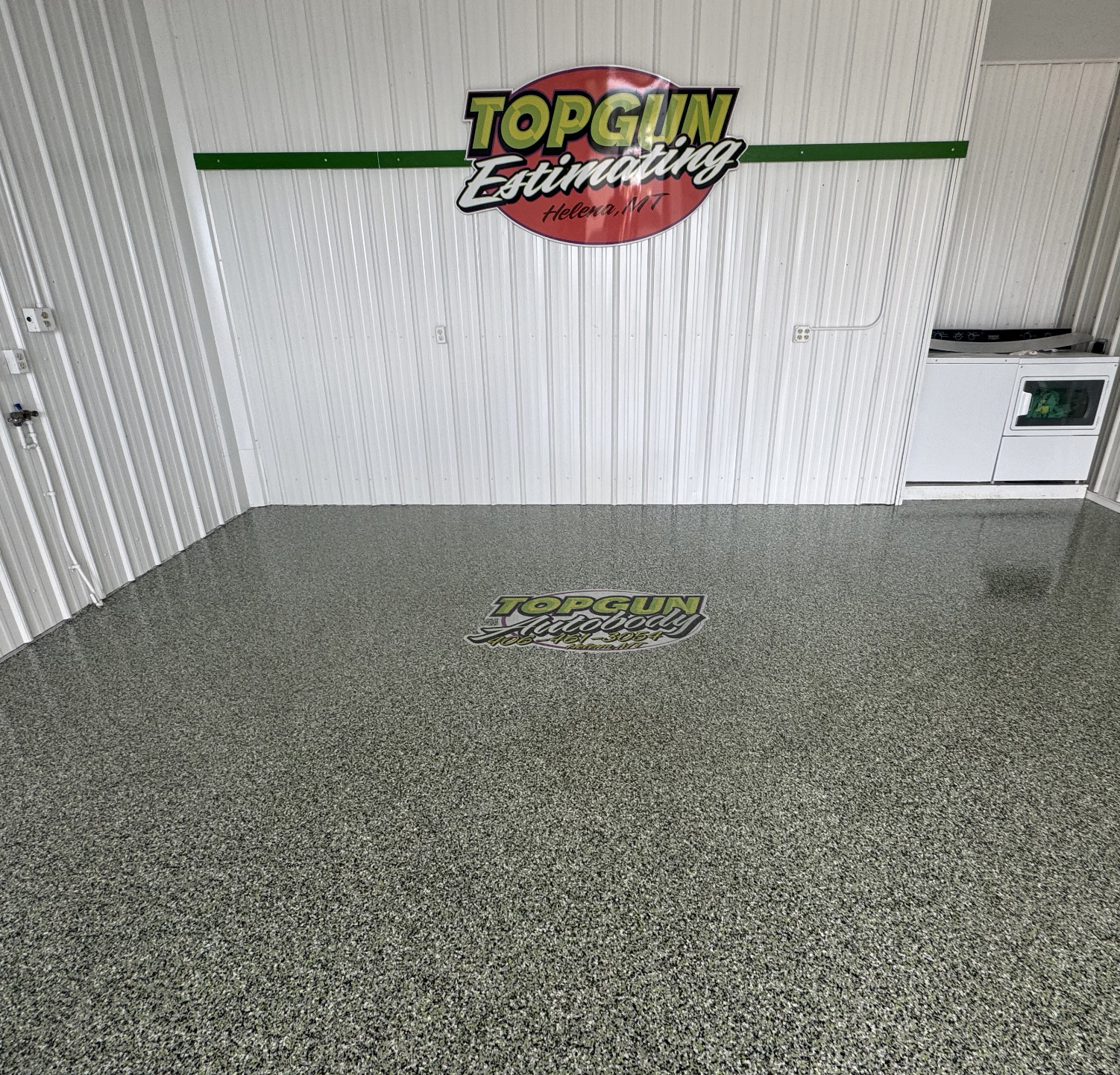 Wall sign and floor decal of Top Gun Endfitting in Helena, Montana inside a building with white paneled walls and speckled gray flooring.