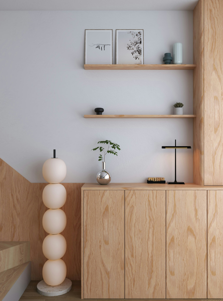 Interior home decor with a light wood cabinet, minimalist shelving holding framed artwork, vases, and a small plant, and a floor lamp with stacked round beige globes.