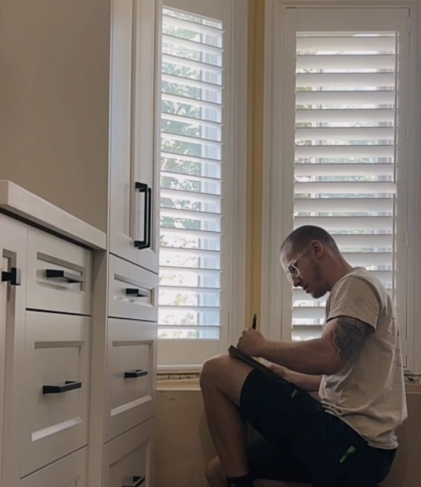 Carpenter taking notes beside custom white cabinetry during an interior project.
