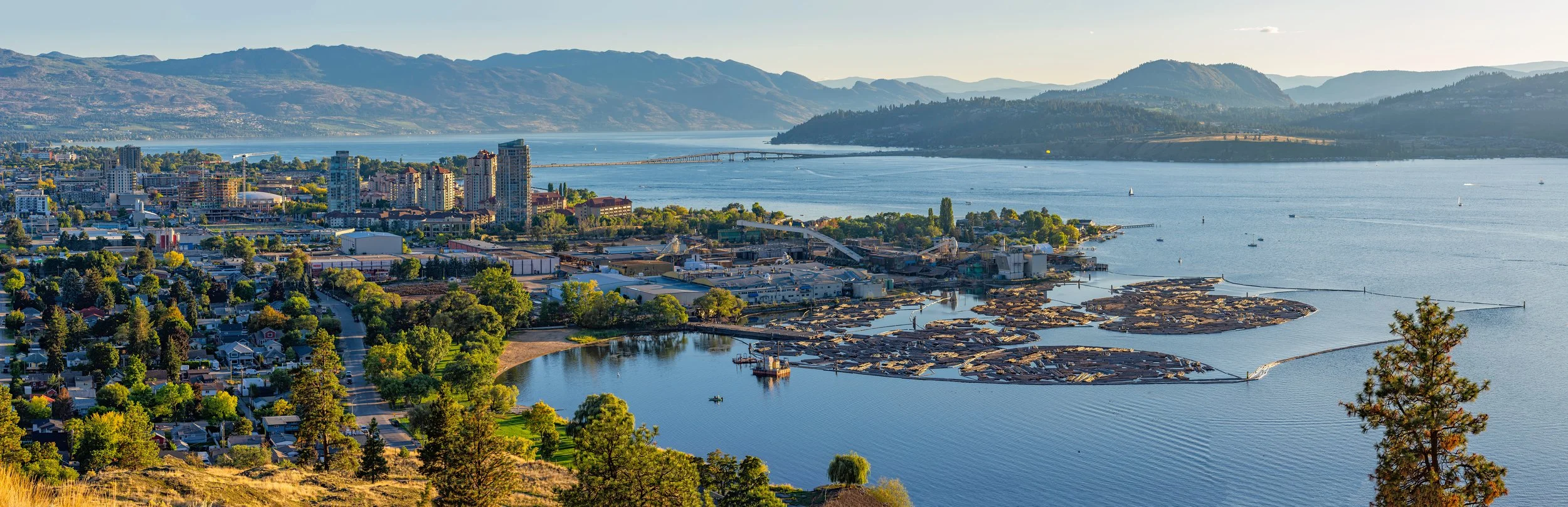 Downtown Kelowna on a beautiful sunny showing lake, floating bridge, mountains and downtown buildings
