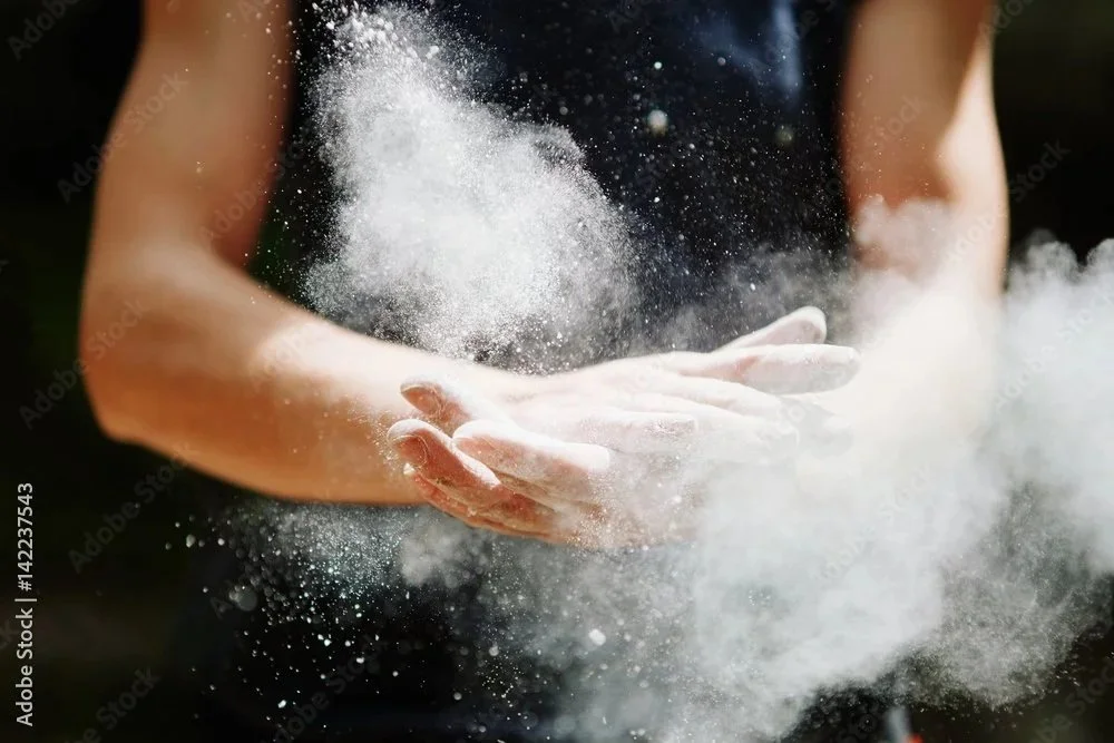 Person sprinkling flour or powder onto hands.