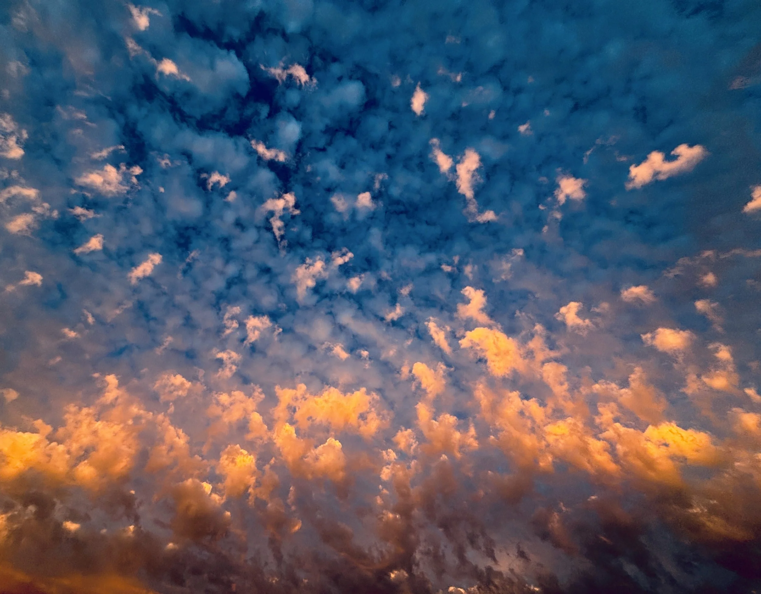 Blick auf den Himmel bei Sonnenuntergang mit orangefarbenen und blauen Wolken.