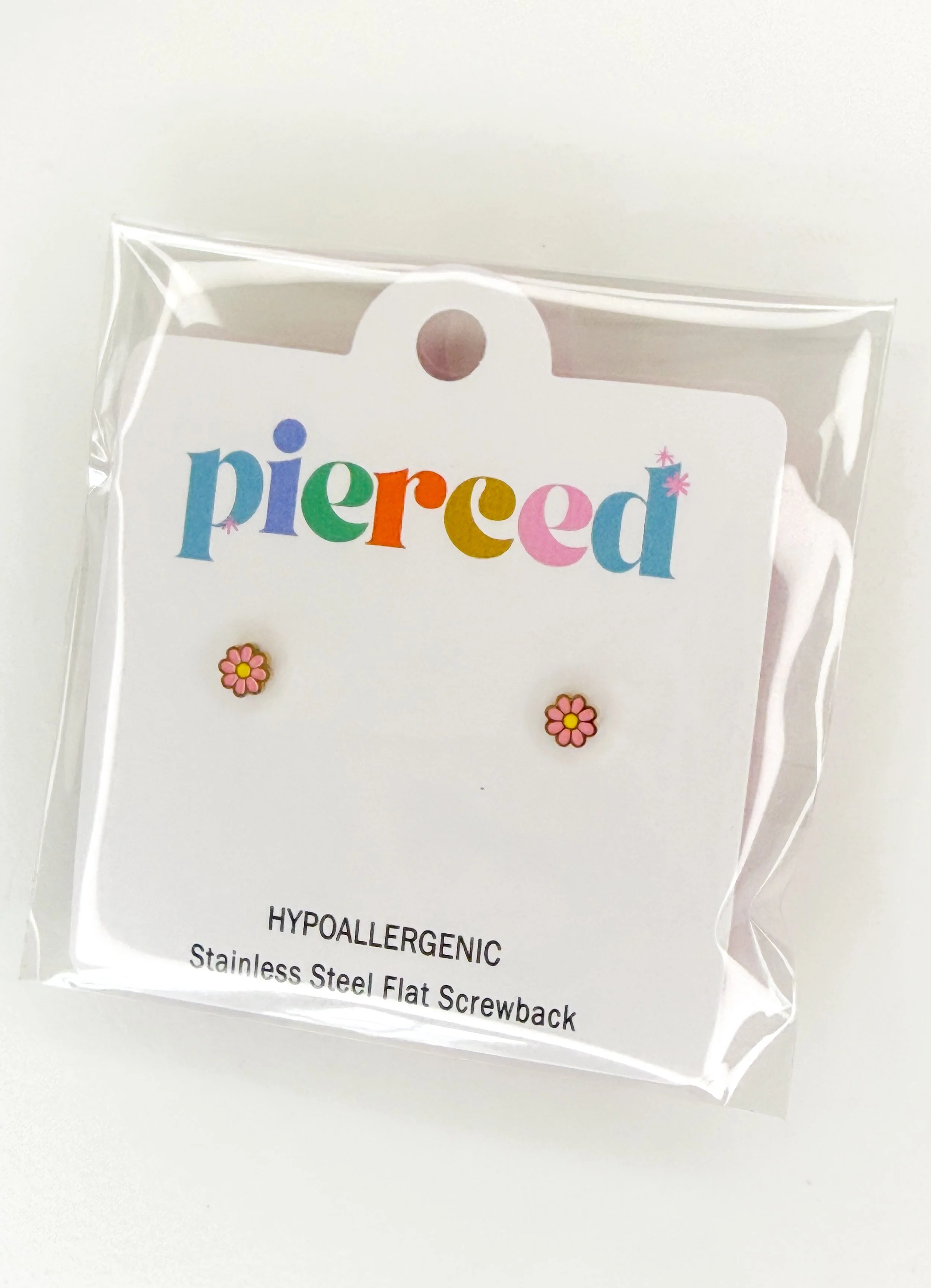 Packaging of a hypoallergenic stainless steel flat screwback earrings with colorful brand name 'Pierced' and small decorative flowers.