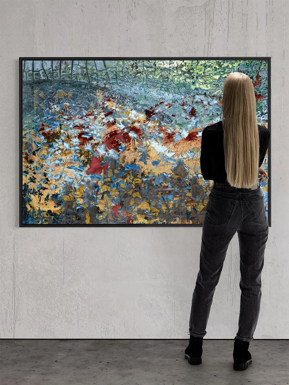 A woman with long blonde hair, wearing a black top and black jeans, stands in front of an abstract painting in a gallery, with her back to the camera.