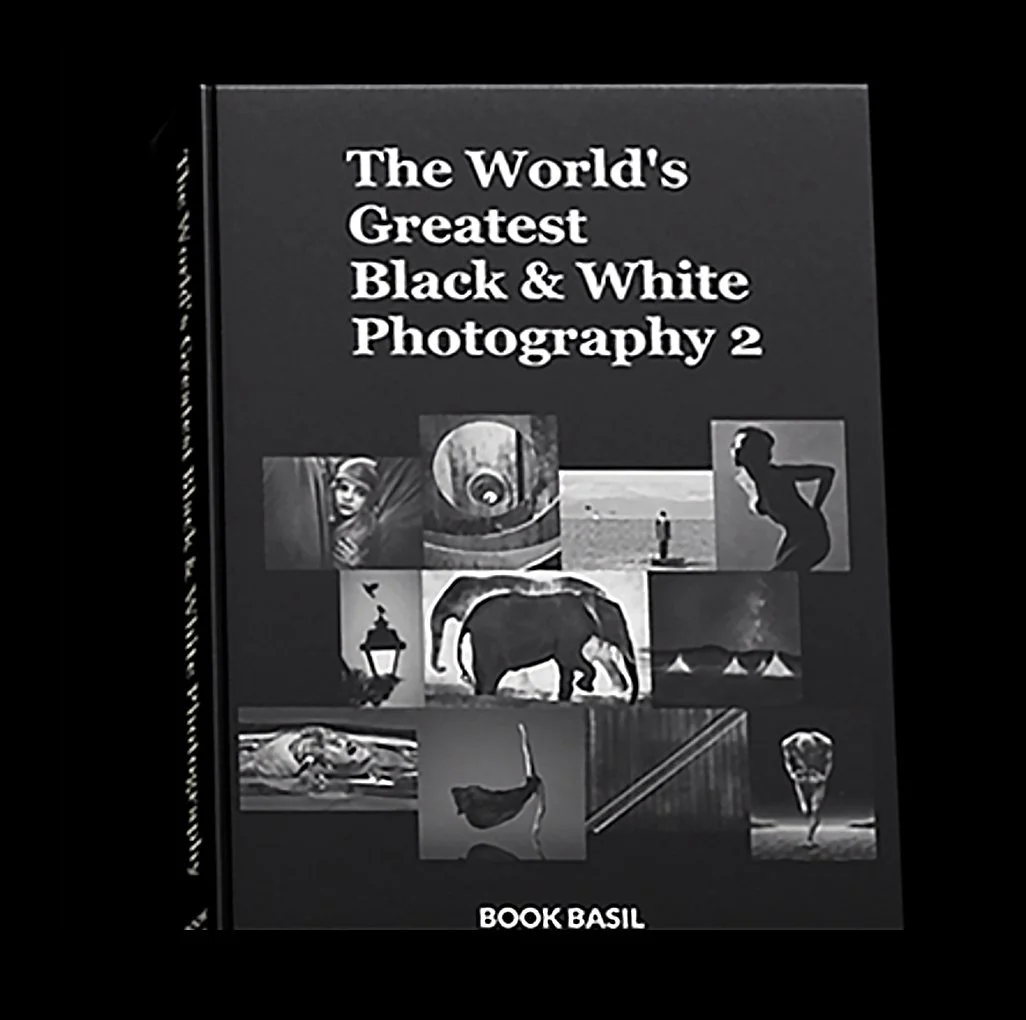 Book cover titled 'The World's Greatest Black & White Photography 2' with various black and white photographs including a woman, an eye, a person on a beach, a silhouette of a woman, a lamp post, an elephant, a bird, a dancer, and a hot air balloon. Publisher: Book Basil.
