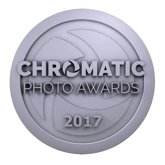 A silver round medal or plaque with the text 'Chromatic Photo Awards 2017' embossed on it.