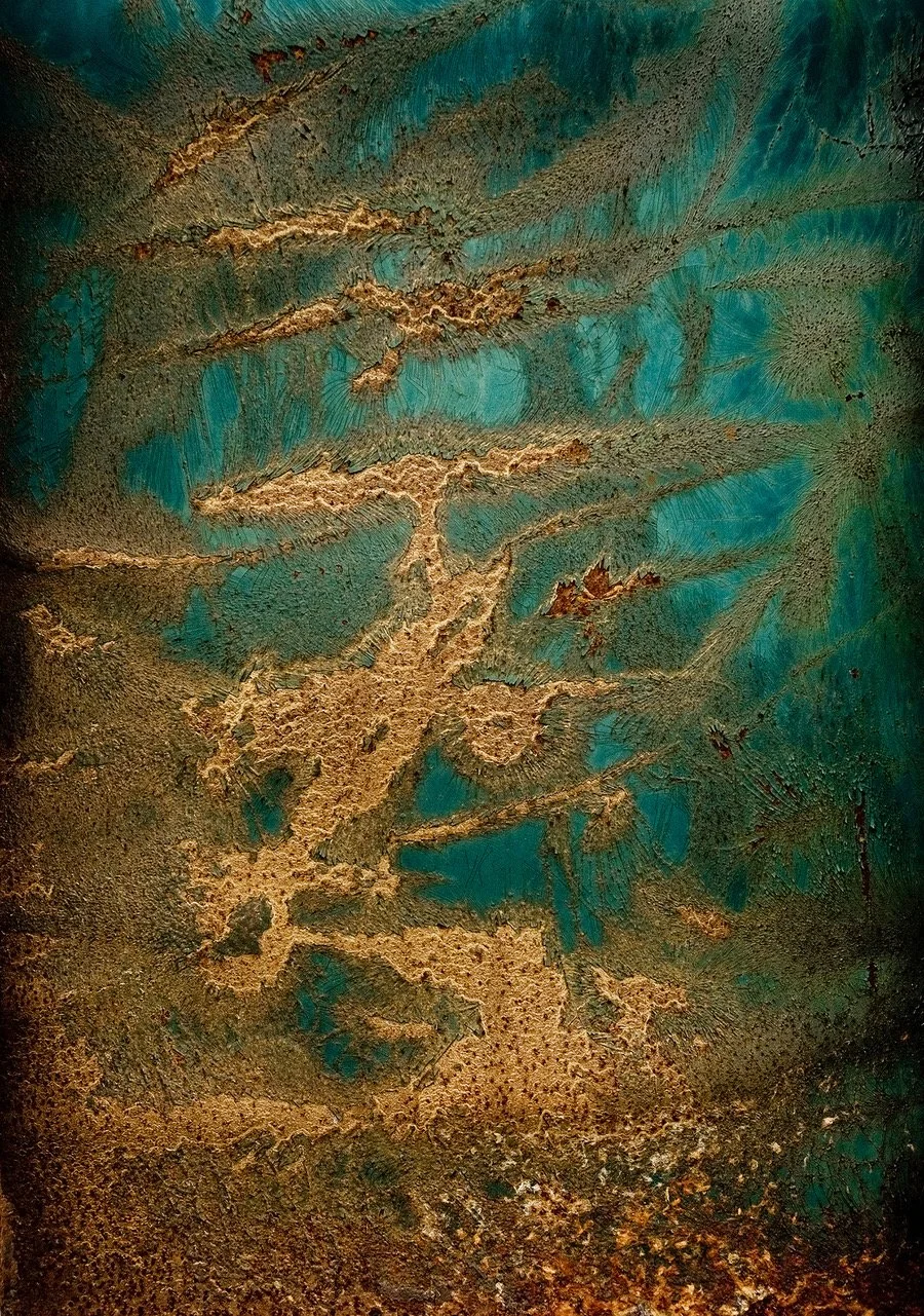 Rusty metal surface with turquoise paint and corrosion patterns resembling abstract shapes.