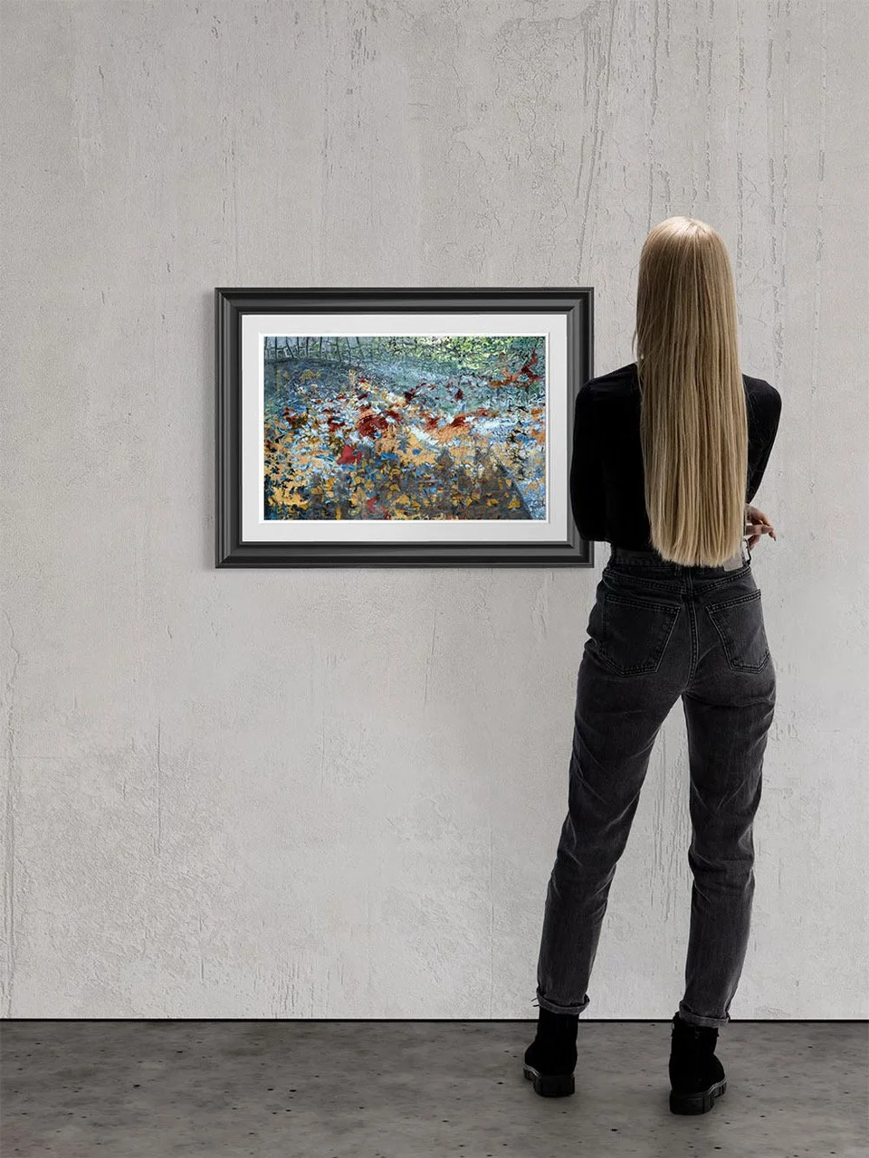 A woman standing with her back to the camera, looking at a painting of a pond with lotus flowers on a gallery wall.