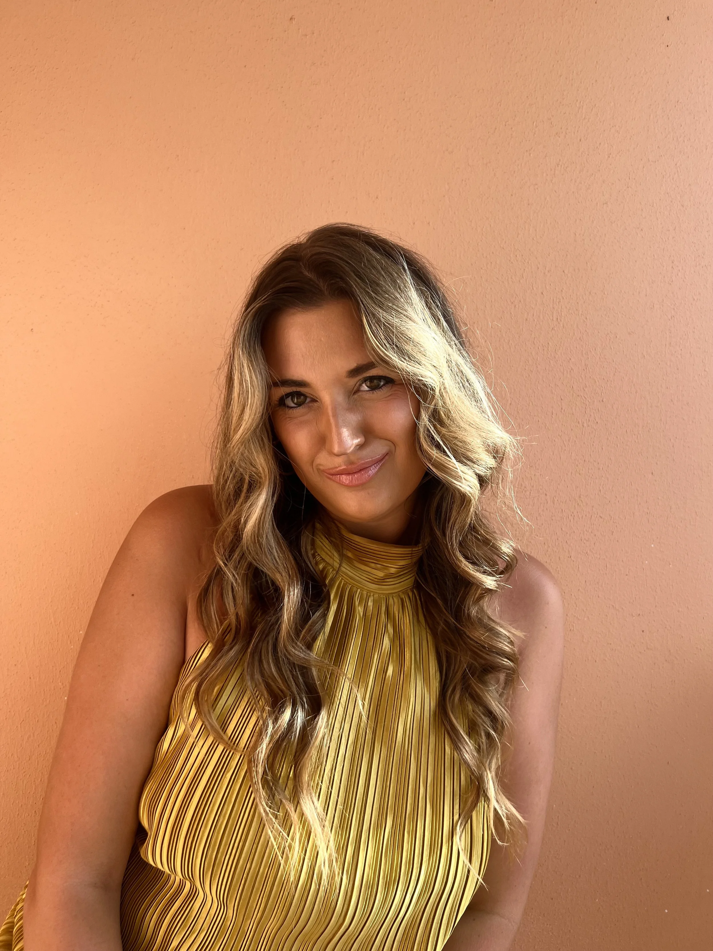 Photo of Samantha Cook in a yellow dress against orange wall