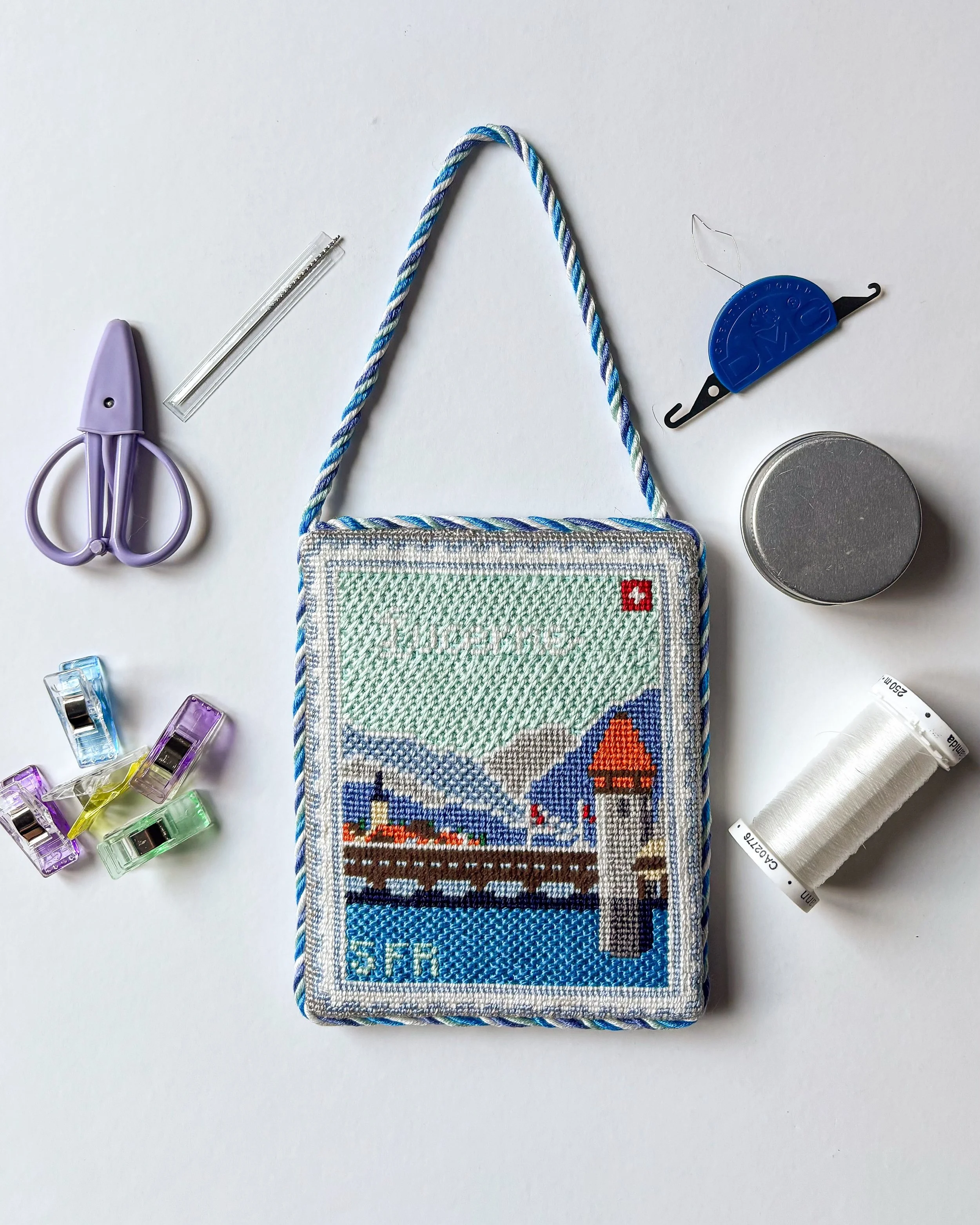 Proof that my finishing studio fits in a tote bag. ✈️🧵

A few favorite finishing accessories and a travel finish. This Swiss travel stamp was the perfect piece to work on for summer! 

Where are you traveling next? 
#needlepoint #finishing #smallbus